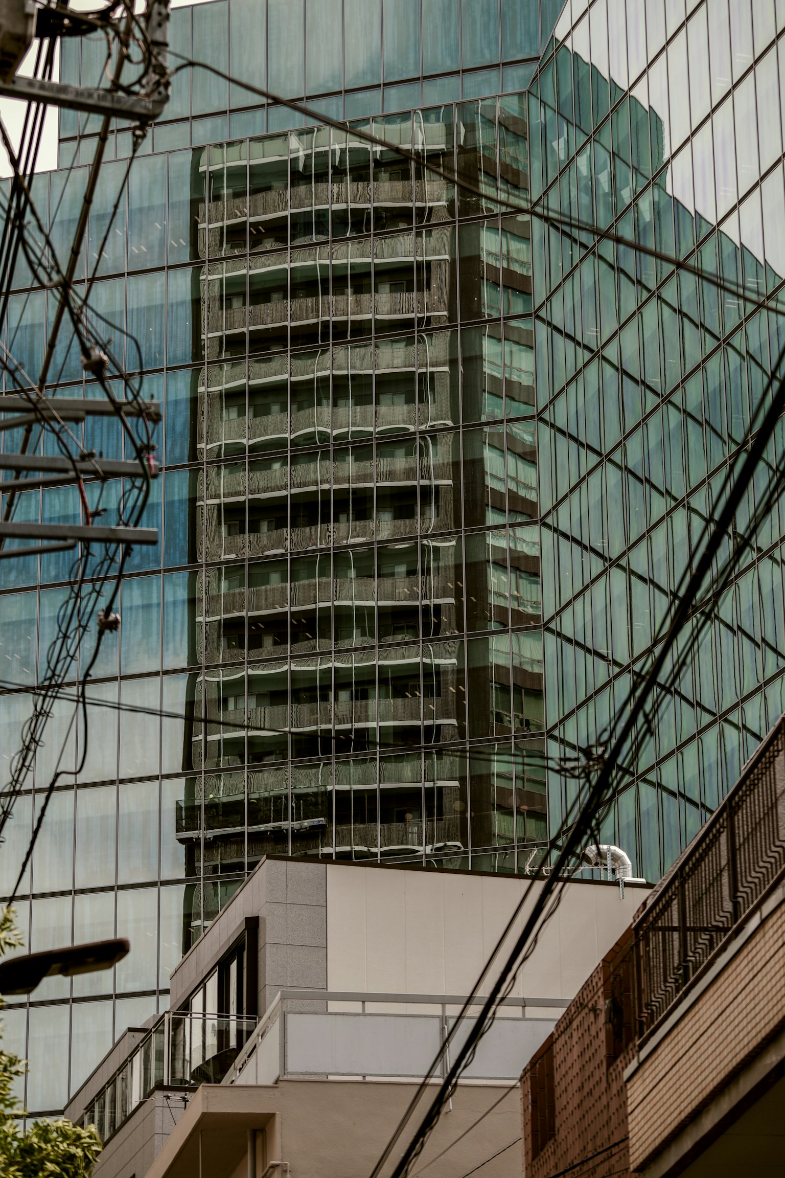 Riflesso di un edificio nel vetro con linee elettriche in primo piano