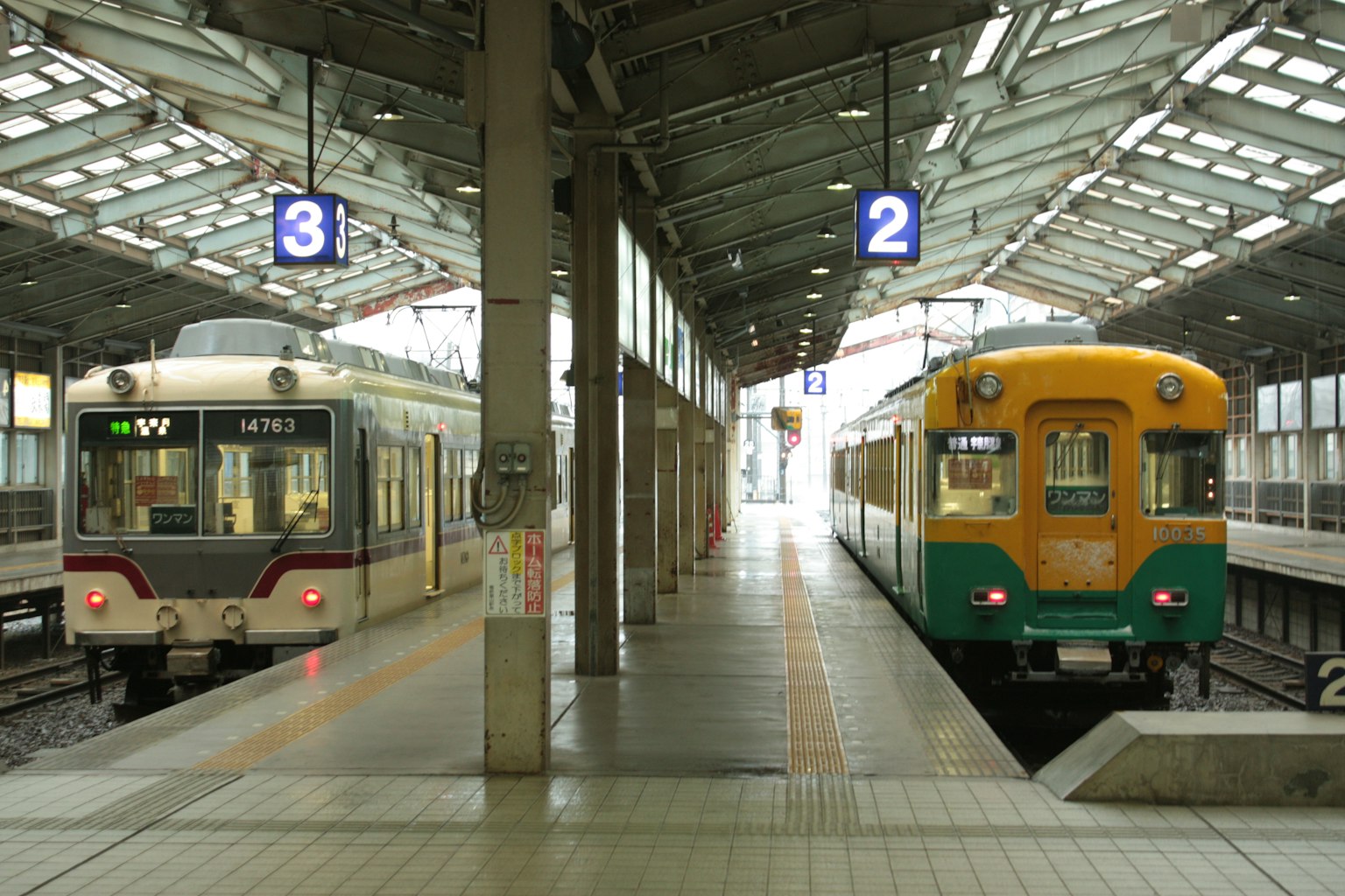 Zwei Züge an einem Bahnhof mit einem hellen Dach