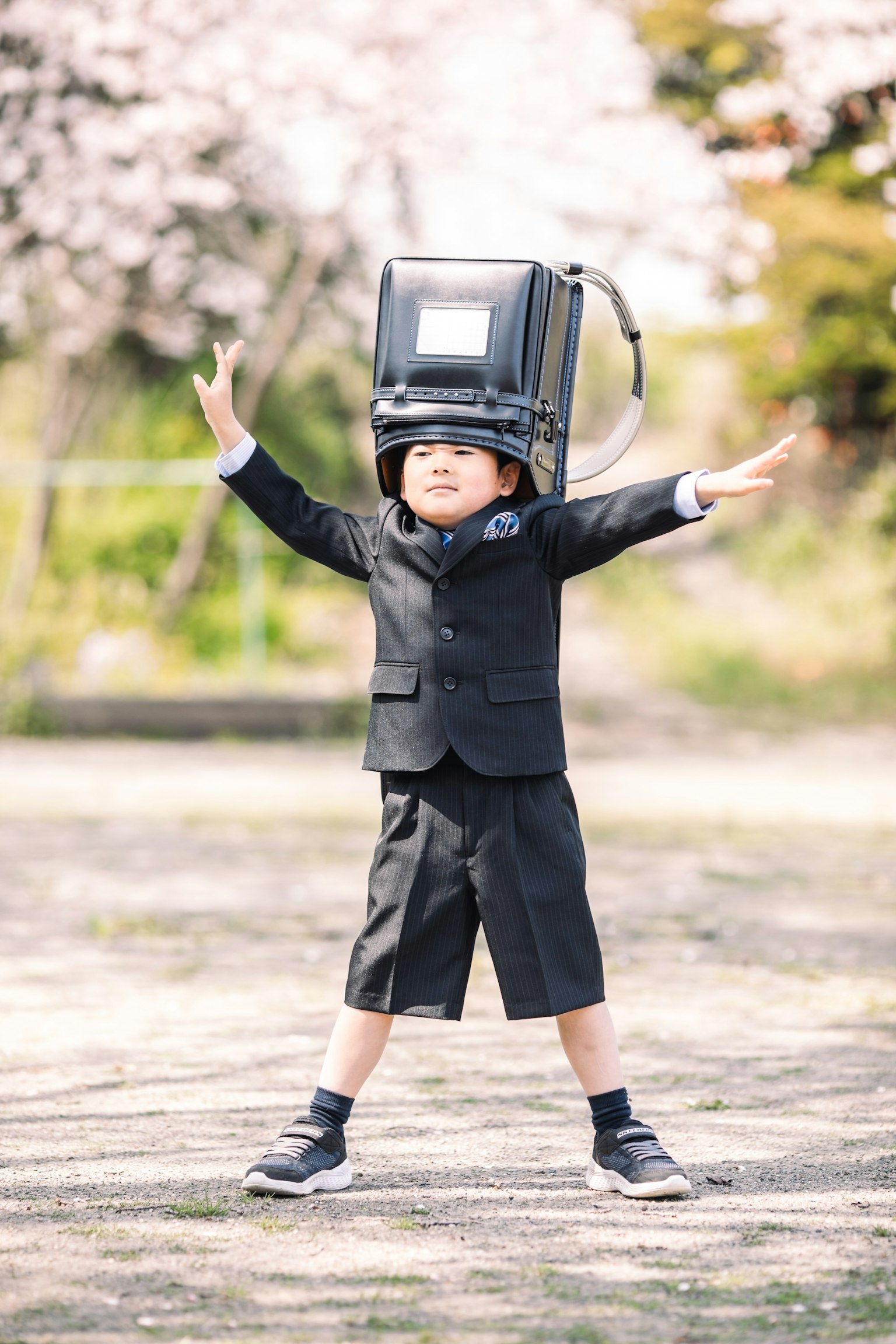 Seorang anak berpakaian jas mengenakan helm las berpose dengan tangan terbuka