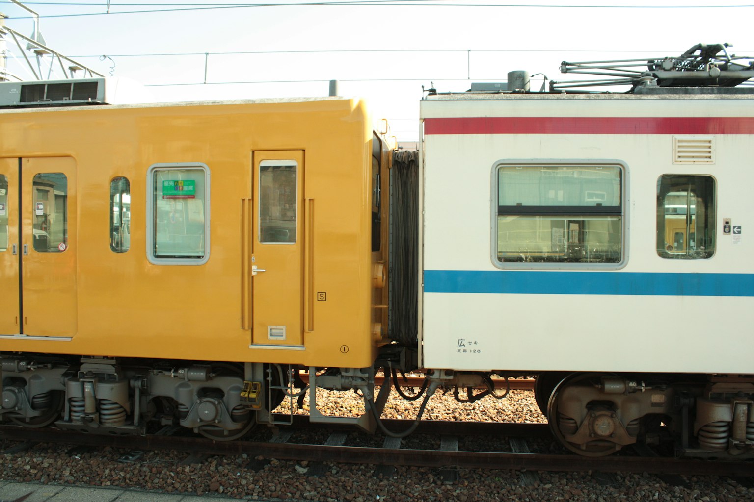 ภาพใกล้ของรถไฟสีเหลืองและรถไฟสีขาวที่เชื่อมต่อกัน