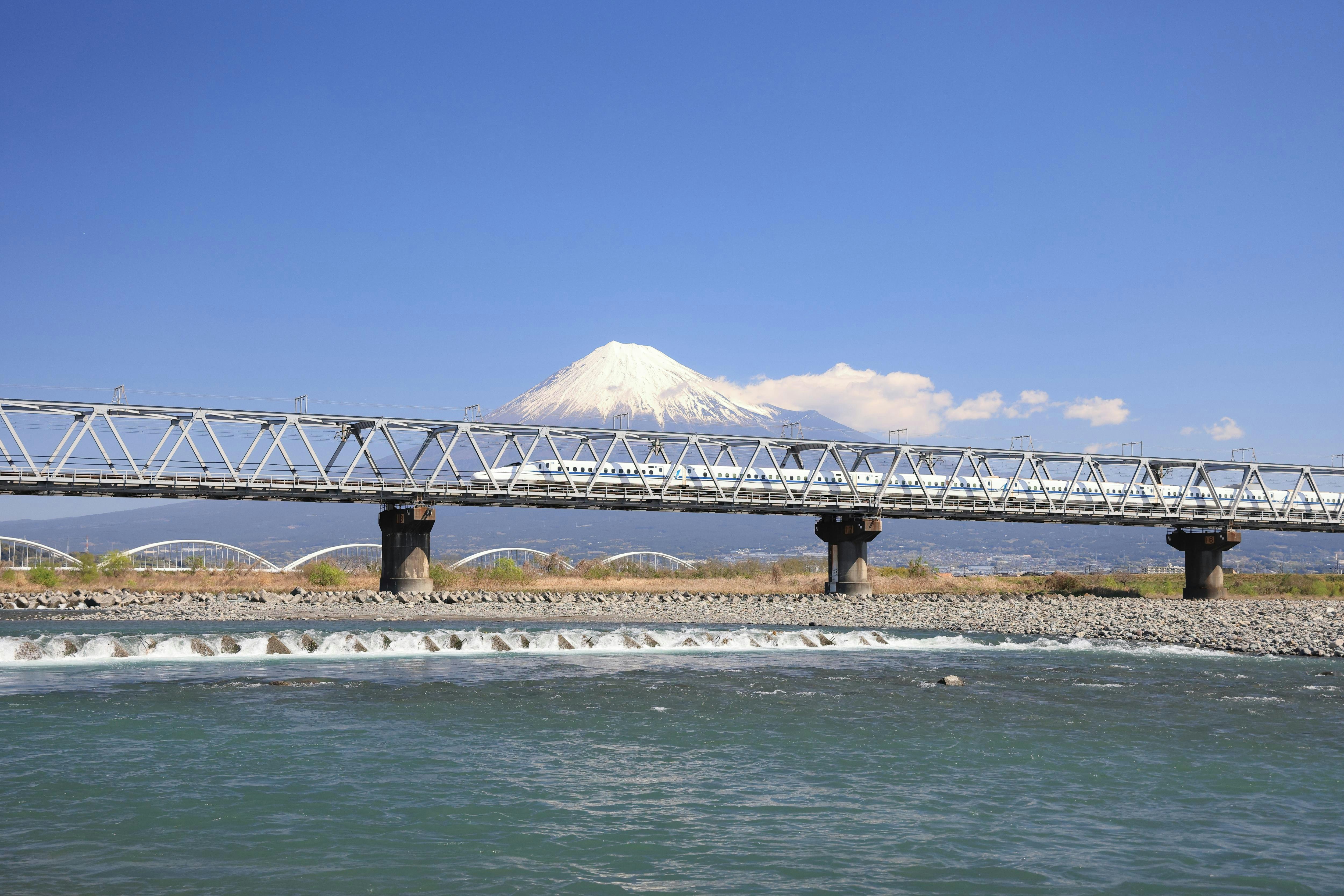 Train Shinkansen passant au-dessus de la rivière Fuji, avec le mont Fuji en arrière-plan
