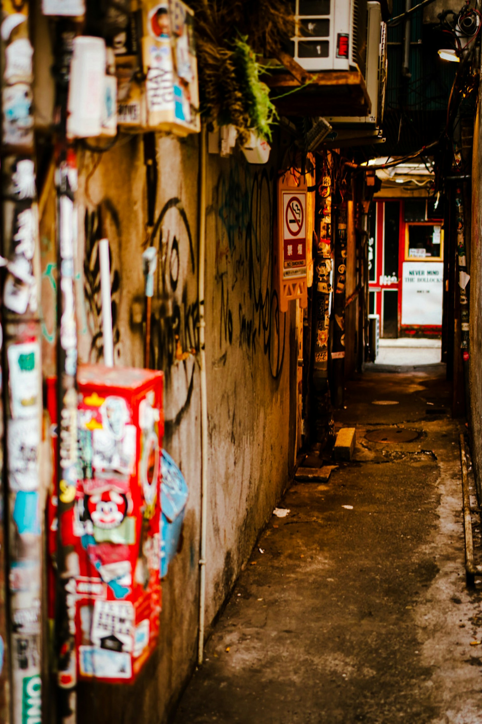 Schmale Gasse mit bunten Aufklebern an den Wänden und einer roten Telefonzelle