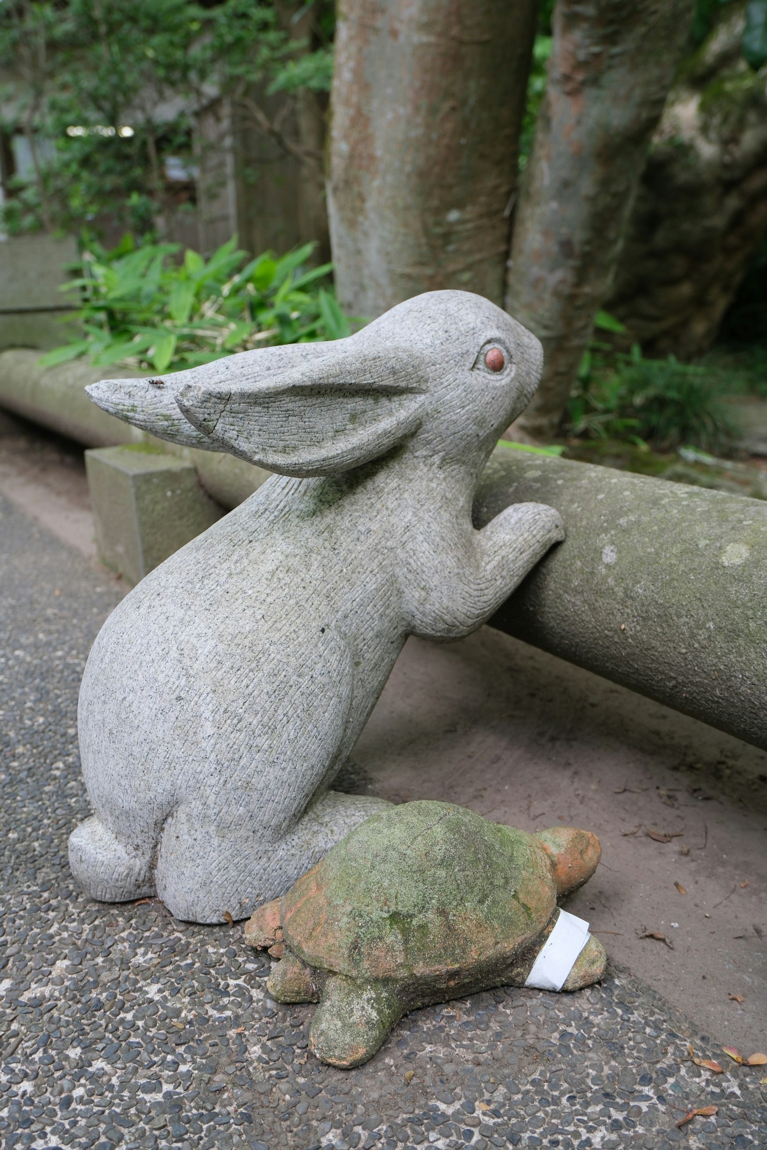 石でできたウサギとカメの彫刻が並んでいる緑の背景