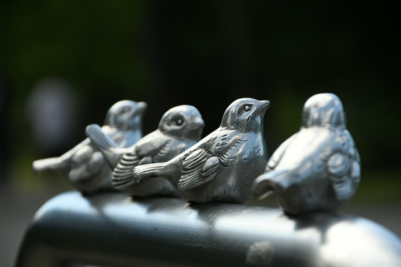 Reihe von Metallskulpturen von Vögeln auf einem Geländer