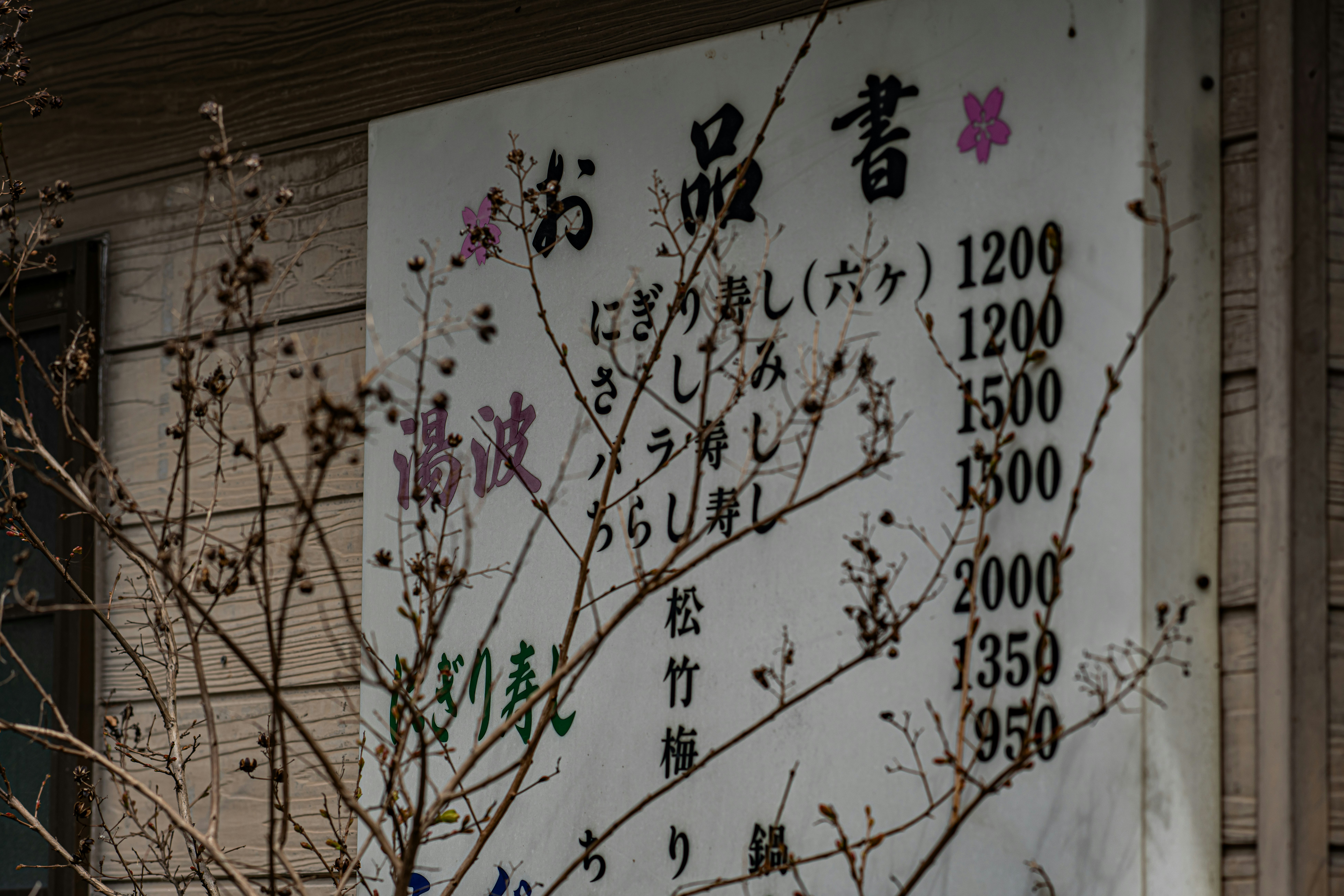 和風の店先に掲げられた価格表と梅の枝の装飾