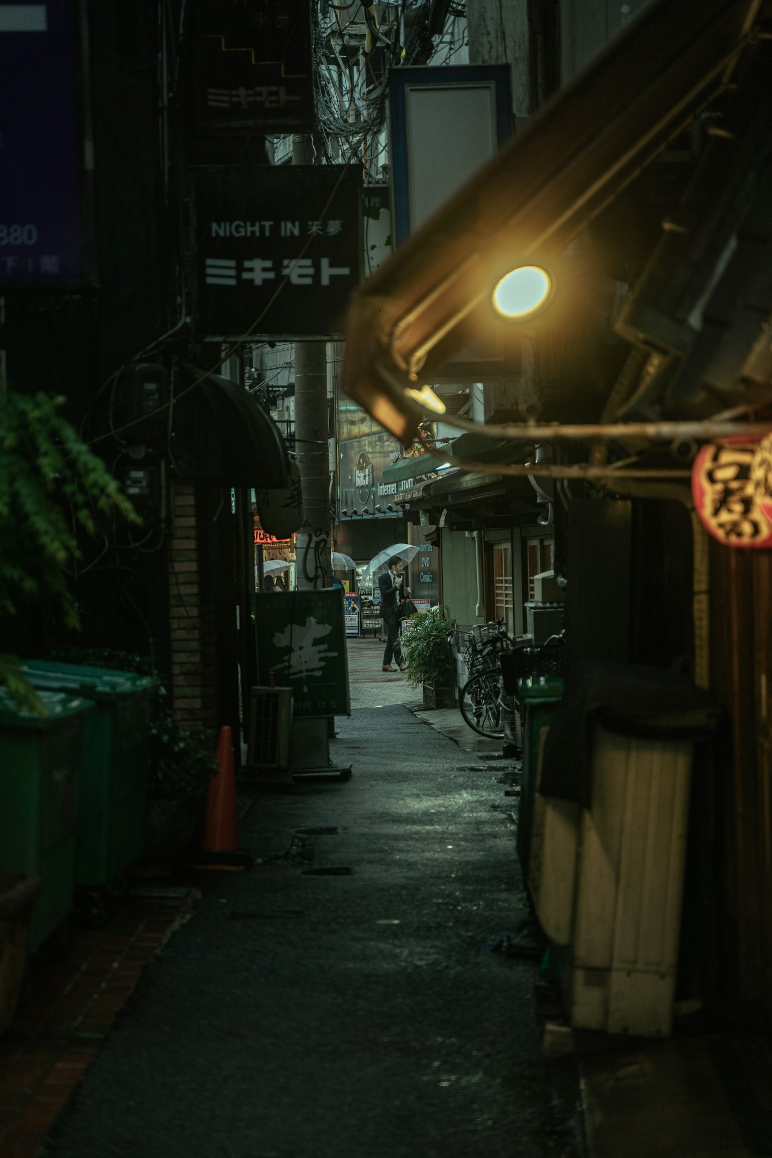 Dimly lit alley with shops and streetlight glow
