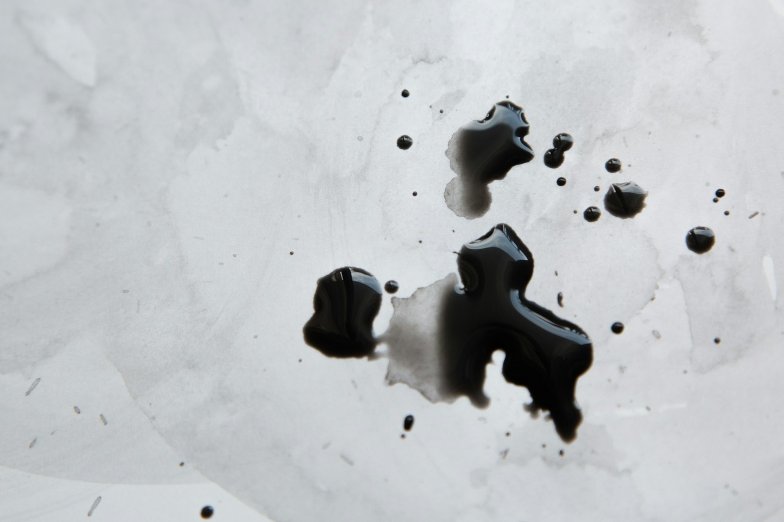 Schwarze Tintenflecken auf einem weißen Hintergrund verstreut