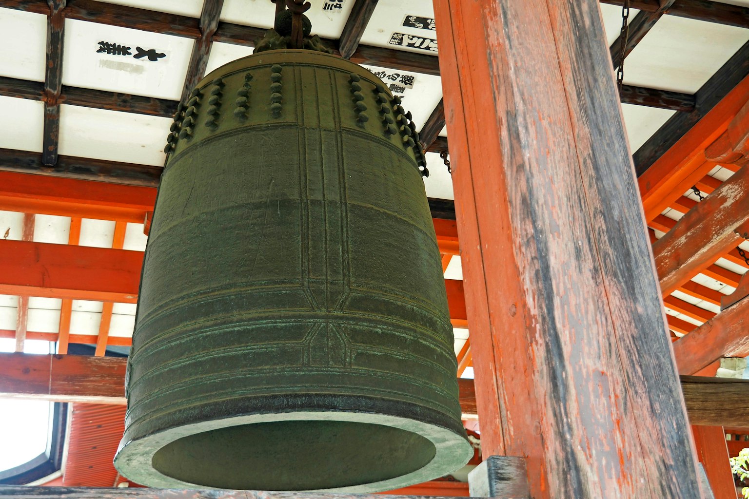 Grande campana di bronzo appesa a travi di legno
