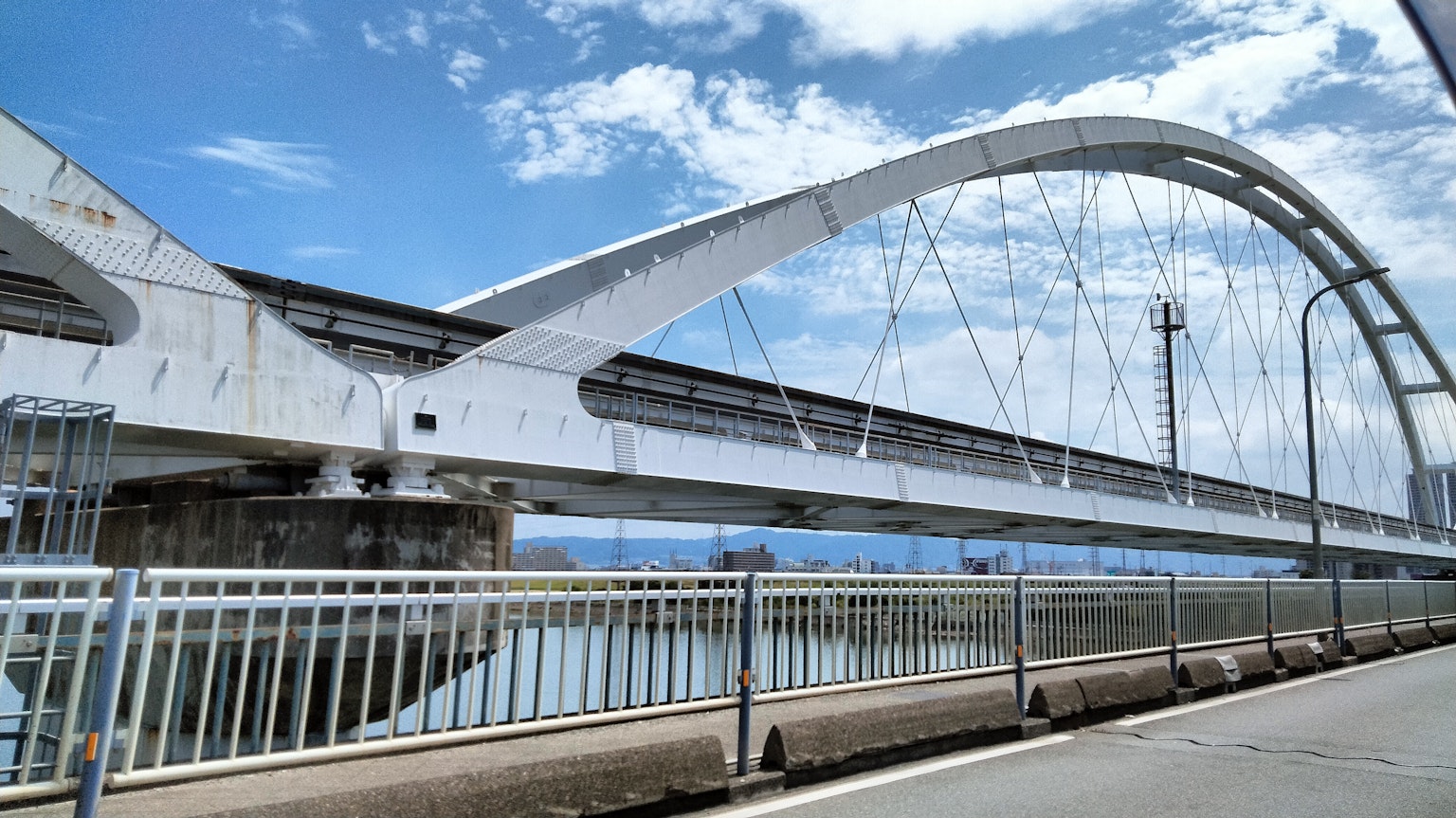สะพานโค้งสีขาวข้ามแม่น้ำใต้ท้องฟ้าสีฟ้า
