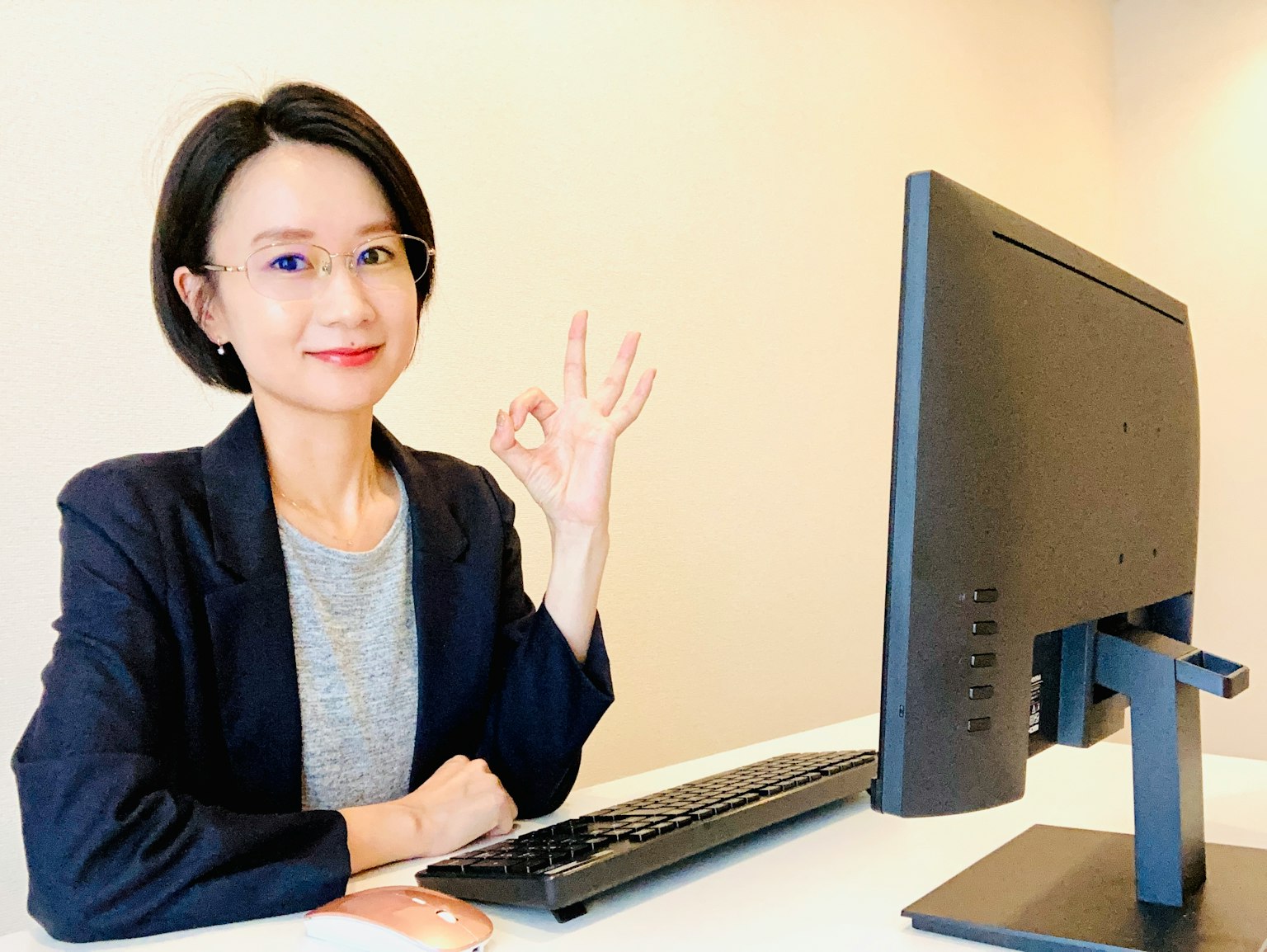 Wanita bisnis yang membuat isyarat OK di depan komputer
