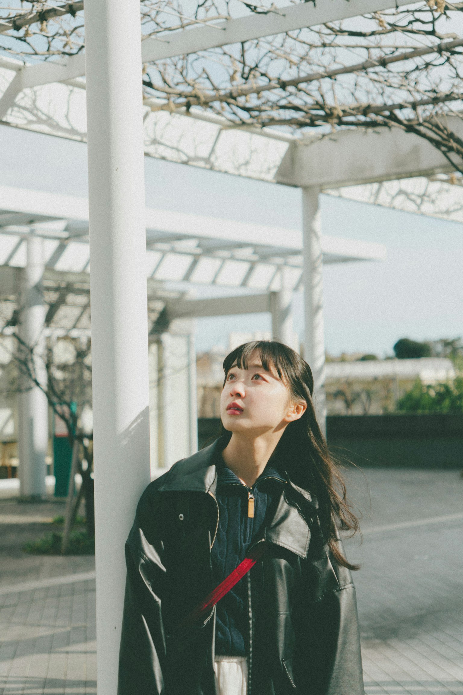 年轻女性在白色柱子旁仰望天空
