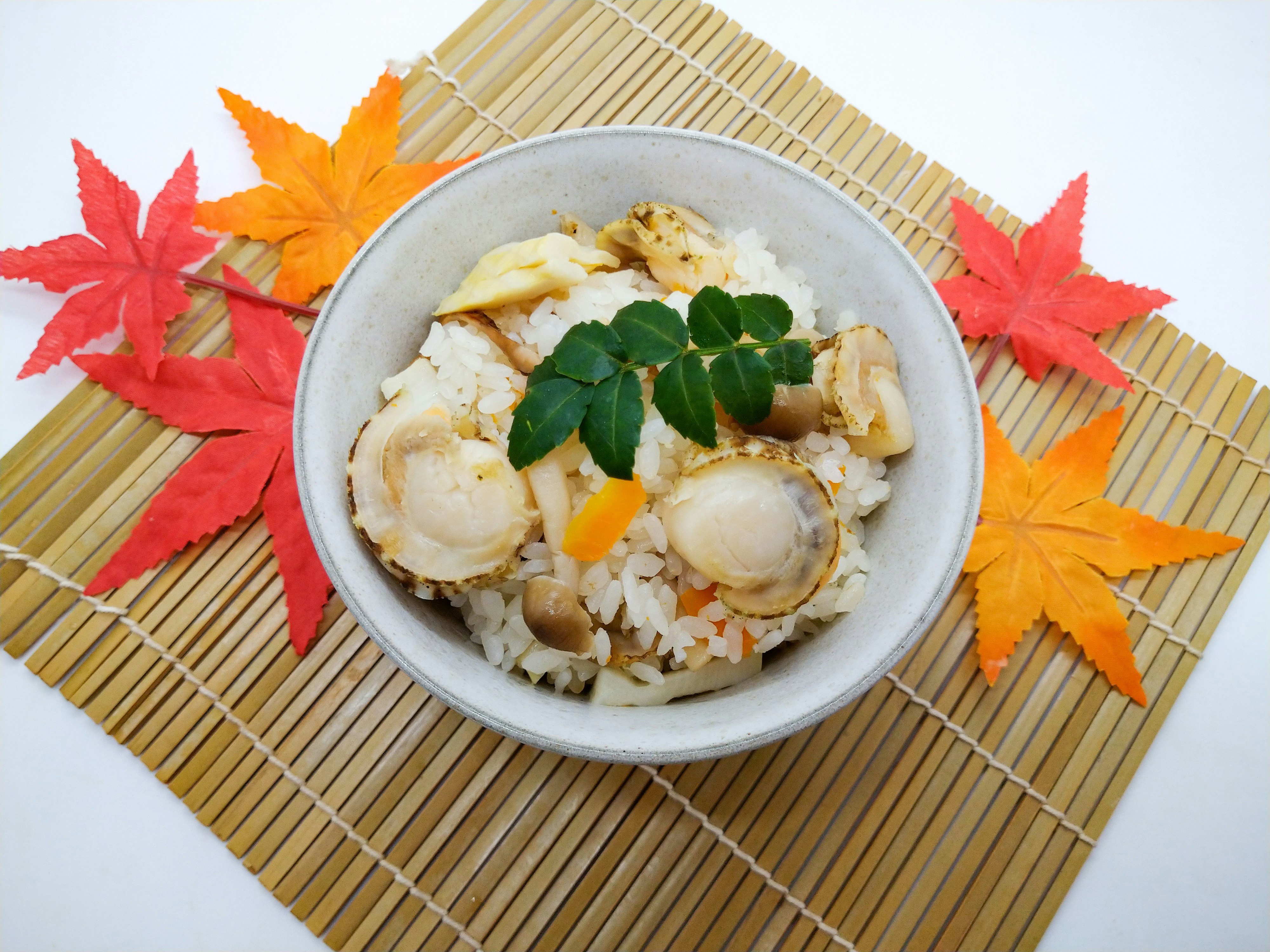 秋の葉を添えた貝の炊き込みご飯のボウル