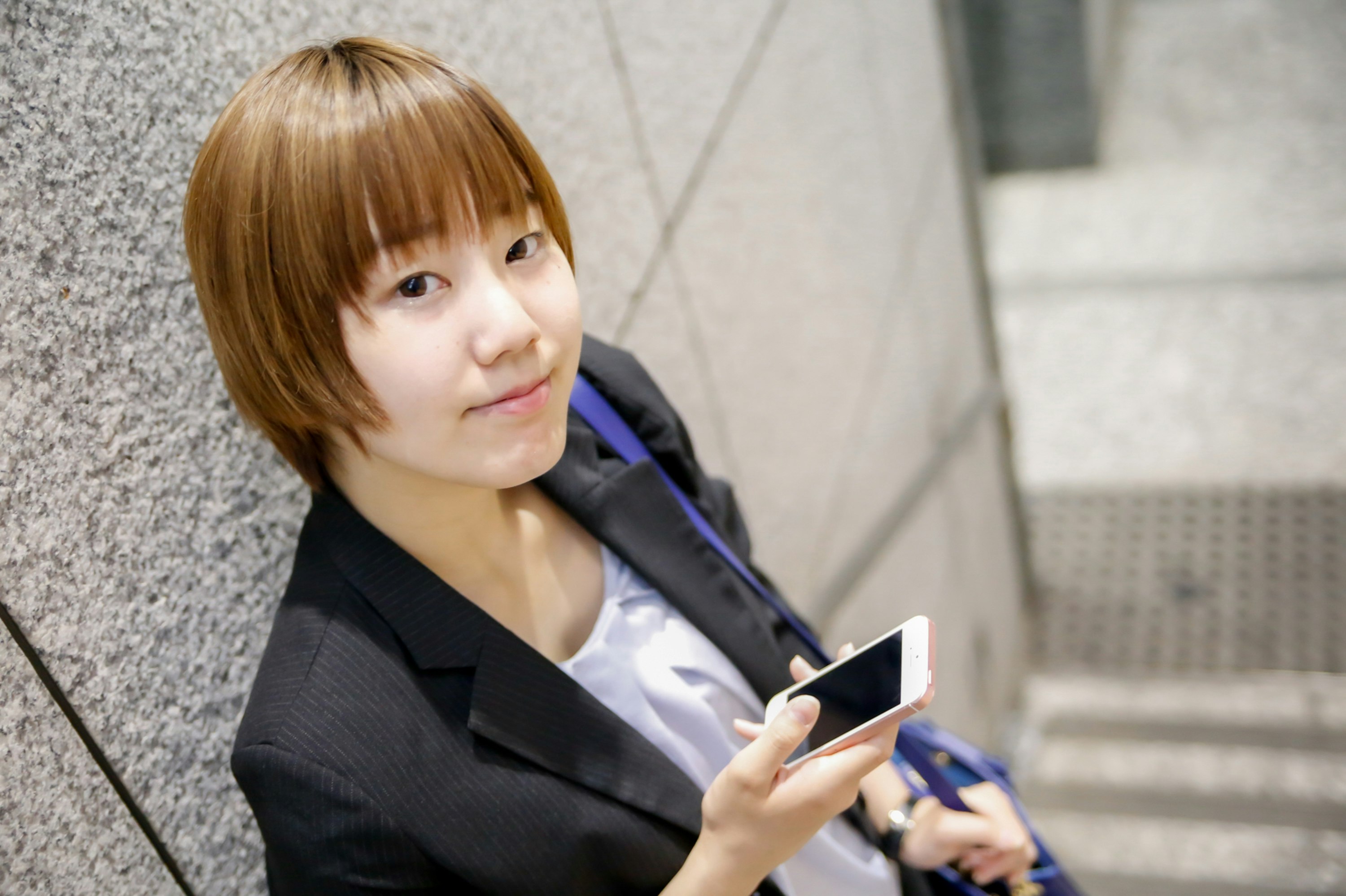 wanita melihat smartphone di depan tangga