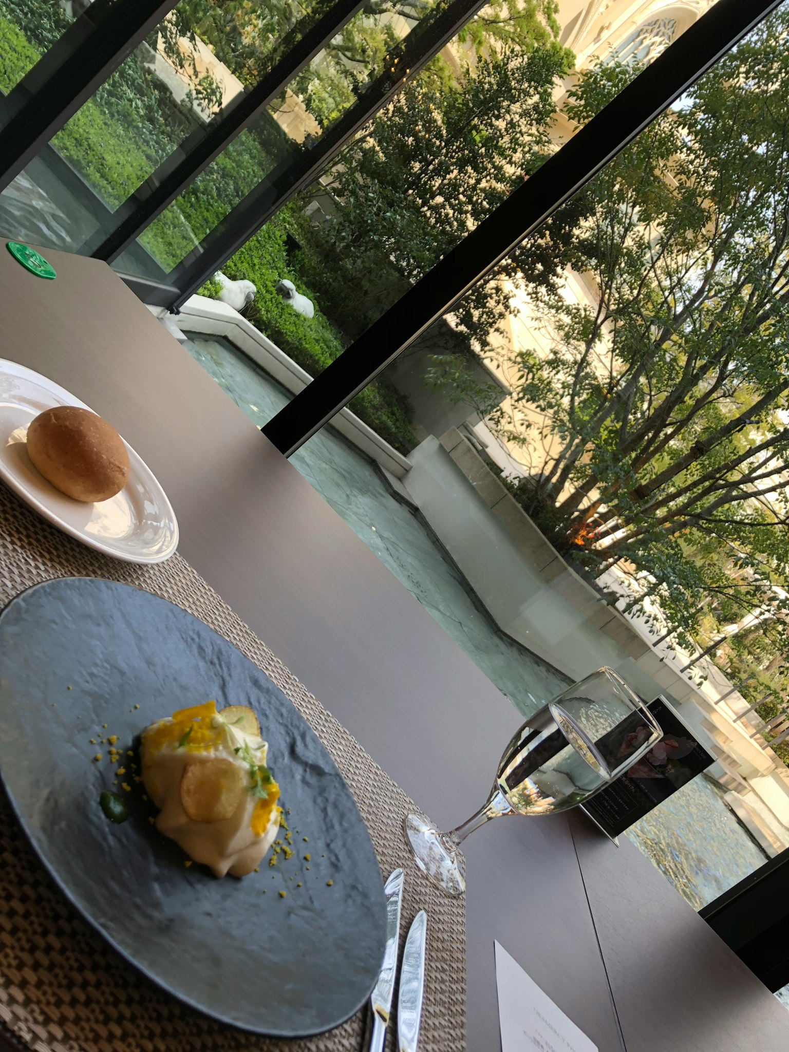 Tisch mit Gourmetgericht und Brot mit Blick auf einen schönen Garten