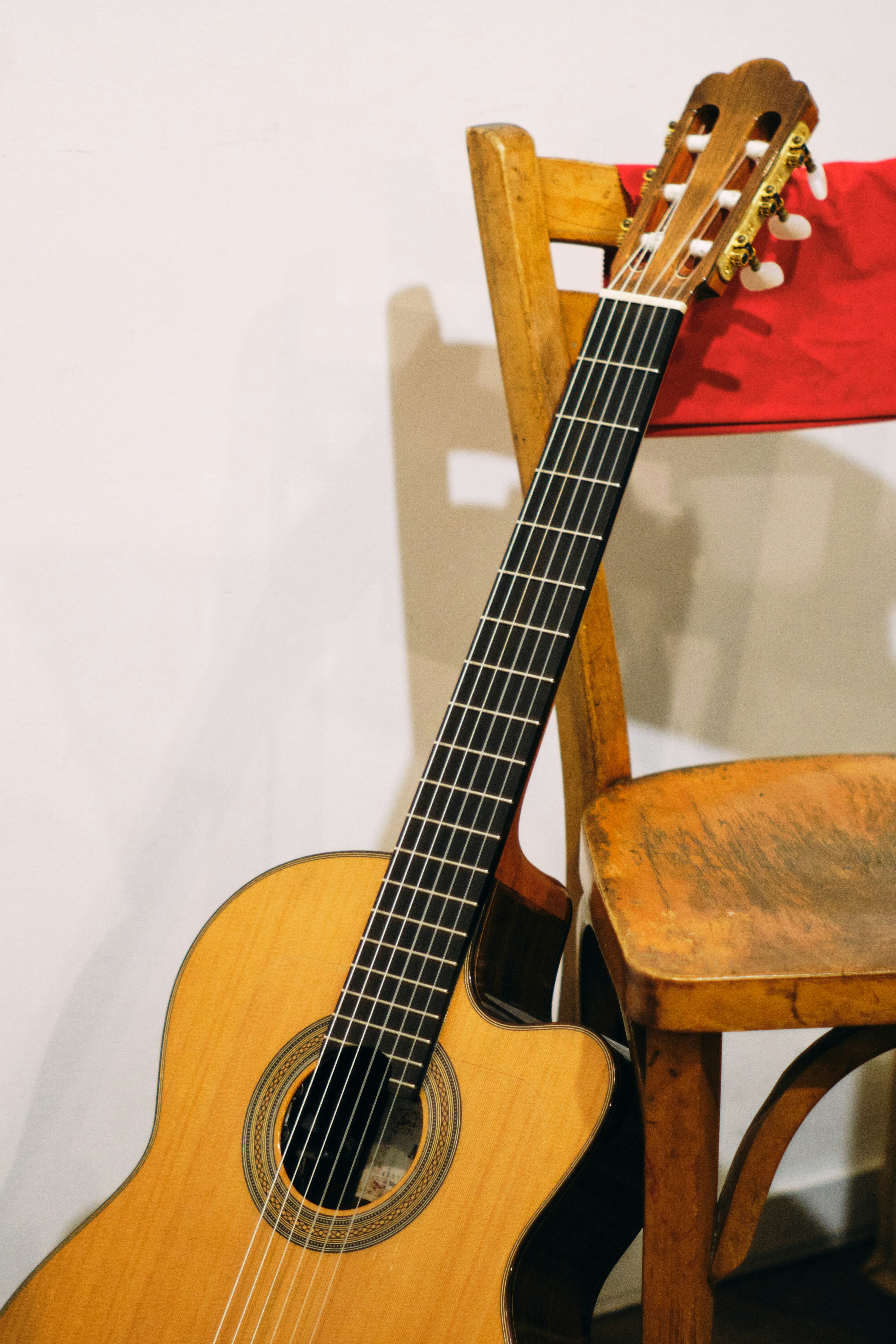 Primer plano de una guitarra clásica junto a una silla de madera