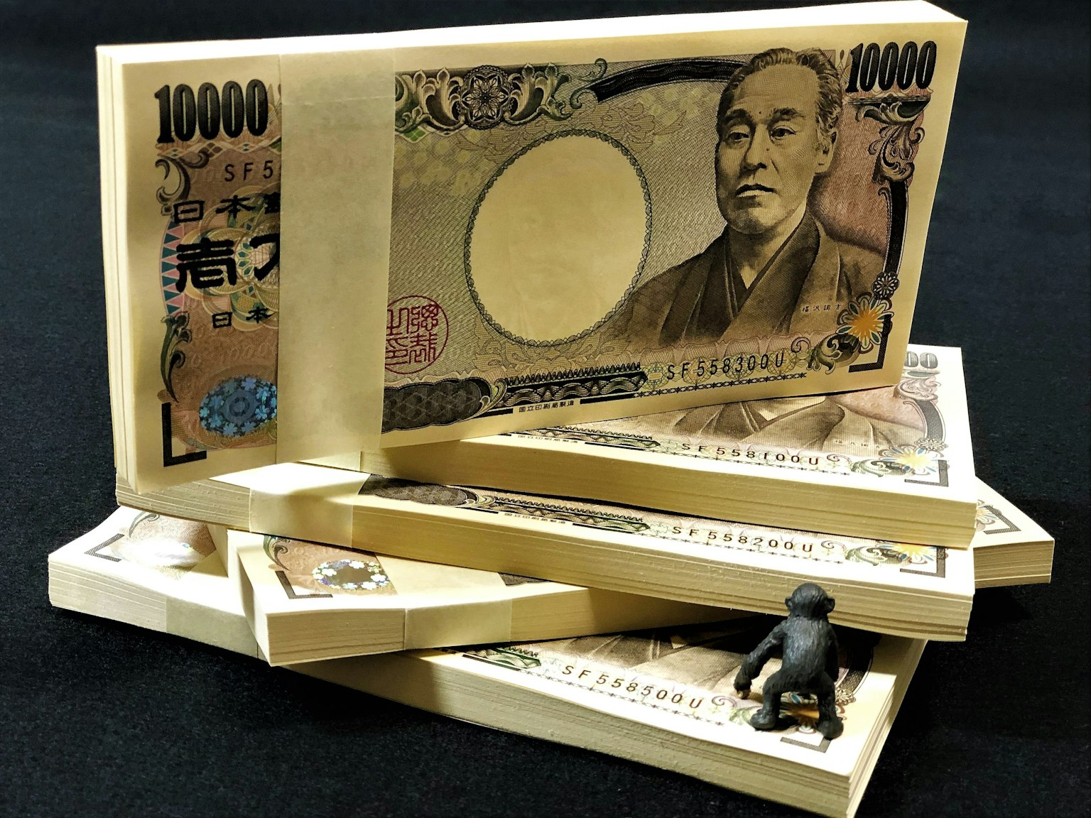 Tumpukan uang kertas 10000 yen Jepang dengan patung kecil