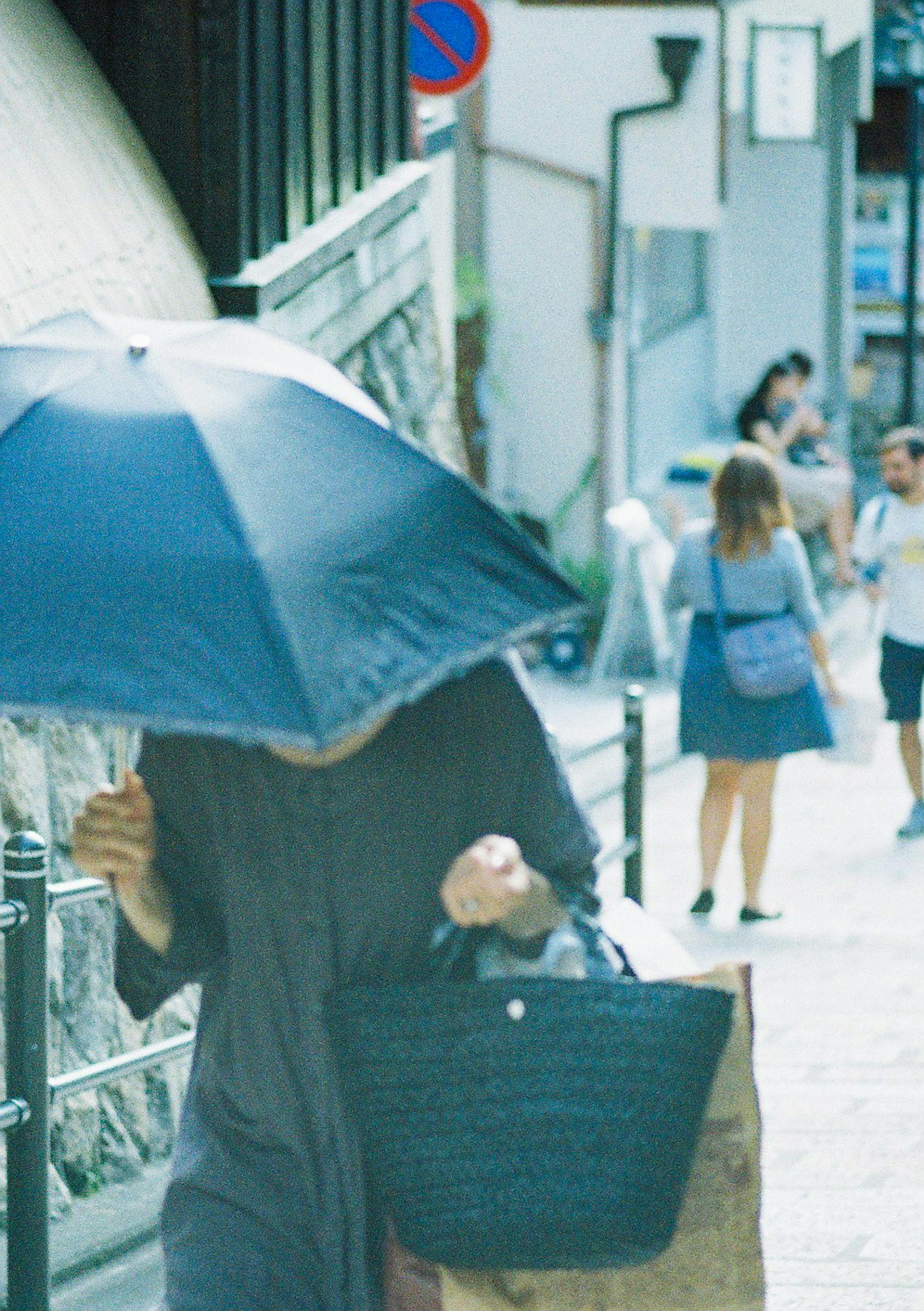 Person walking with an umbrella and background pedestrians