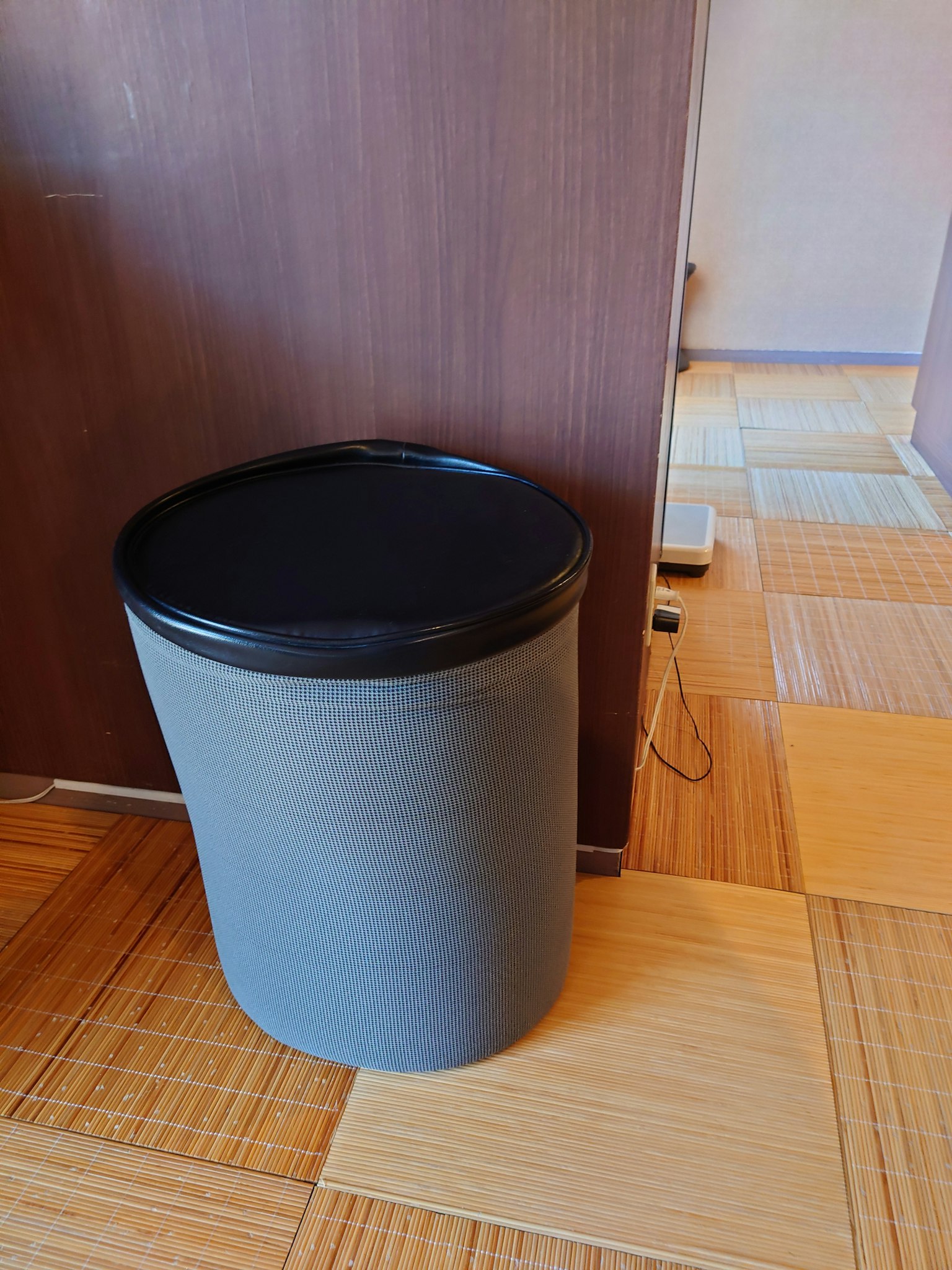Tempat sampah abu-abu diletakkan di samping dinding
