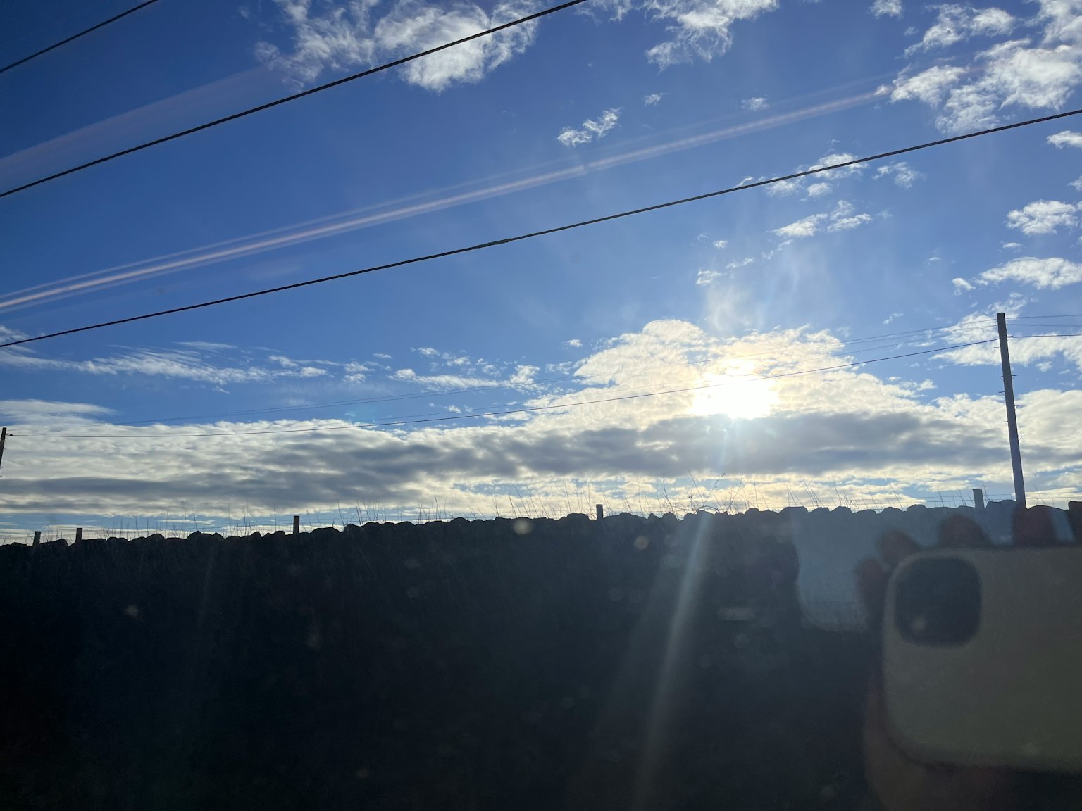Bright sun shining over a blue sky with clouds