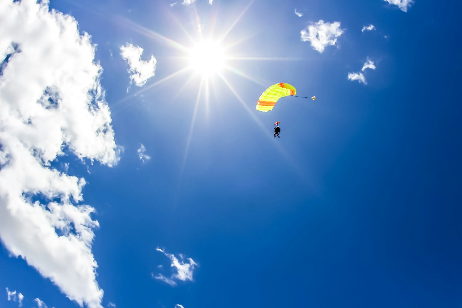 Orang yang turun dengan parasut kuning di langit biru cerah
