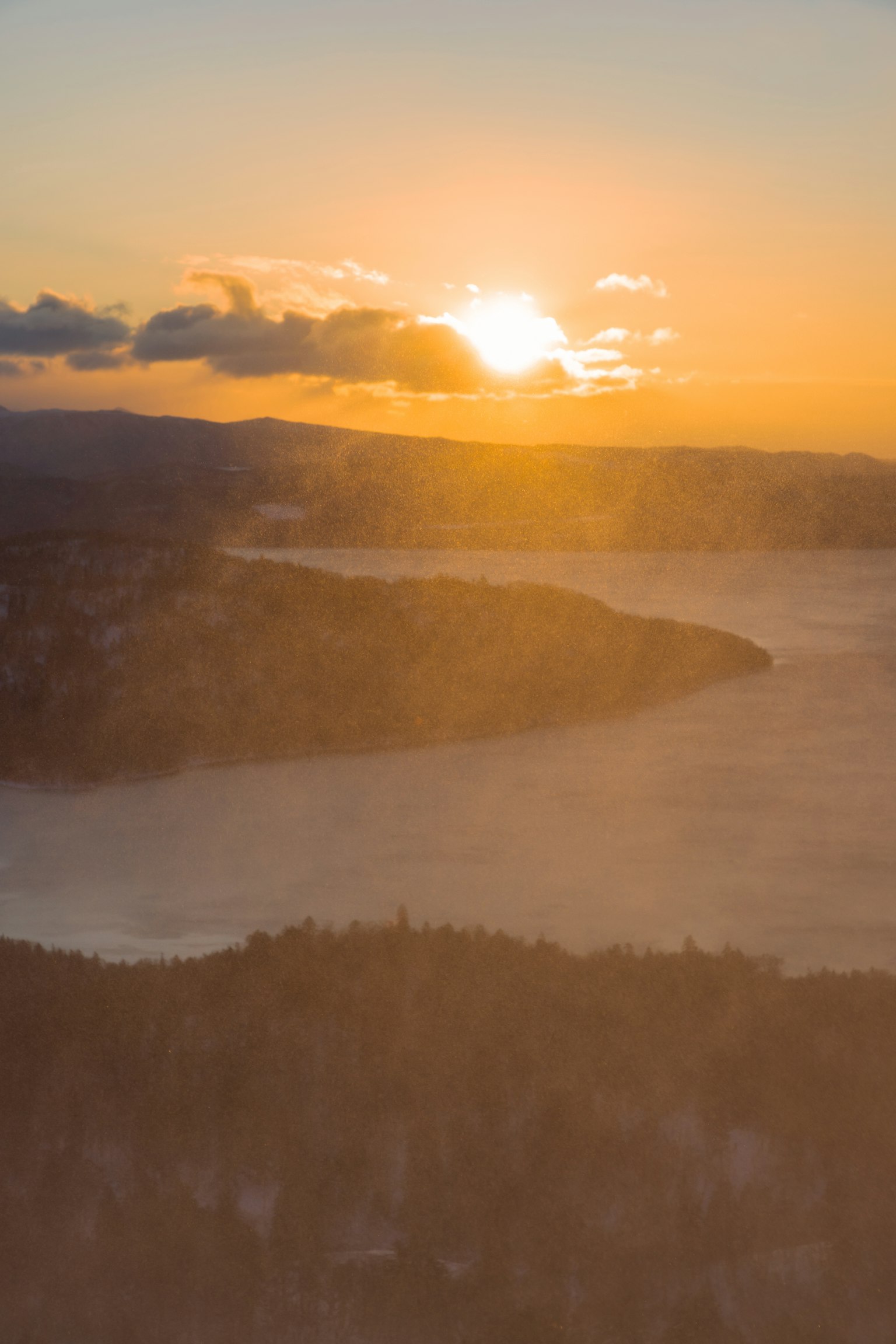 Tramonto su un lago con colline in lontananza