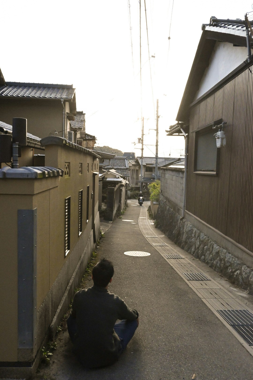 A quiet moment of a person sitting along the alley wall