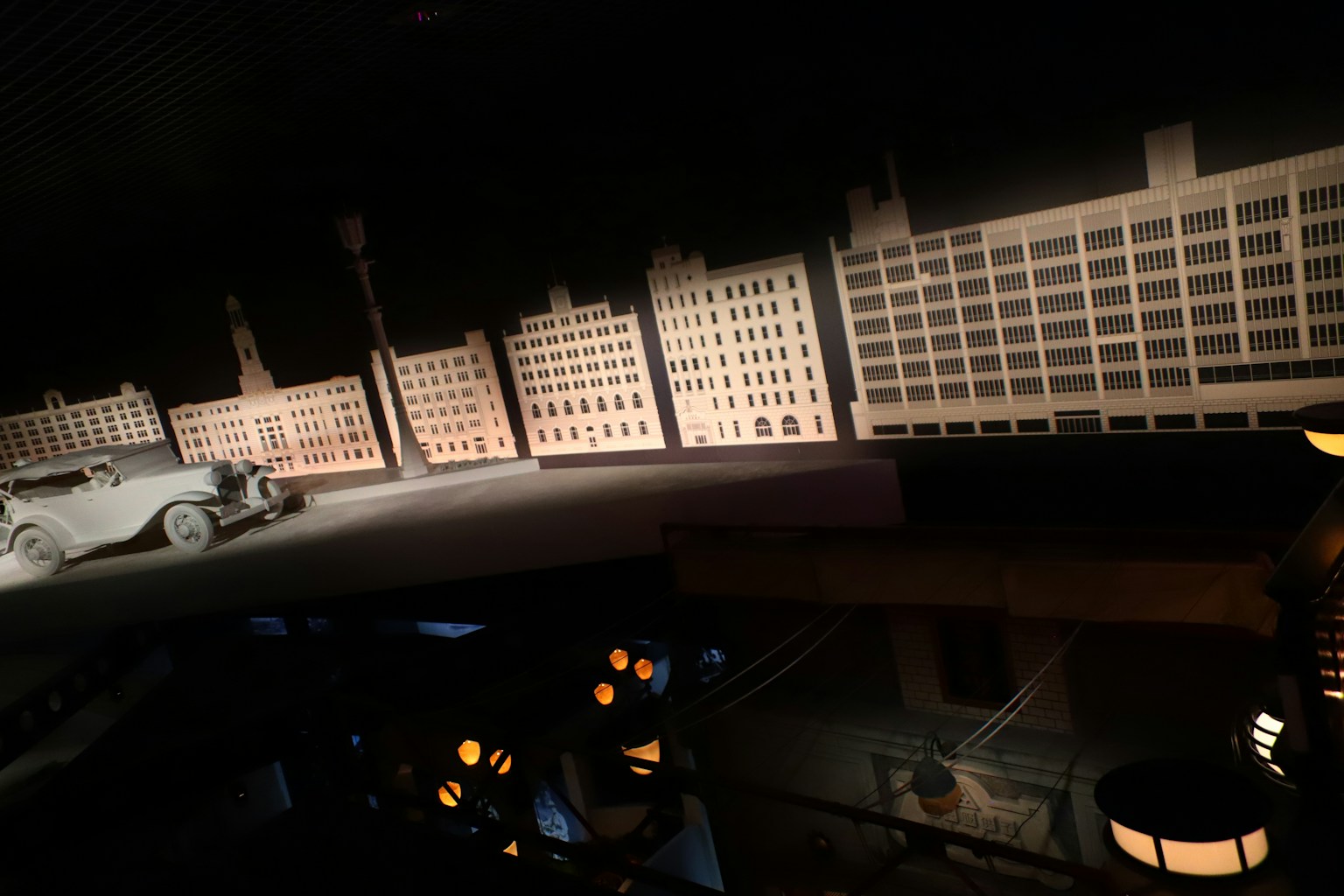 Maquettes de bâtiments et voiture ancienne dans un cadre sombre