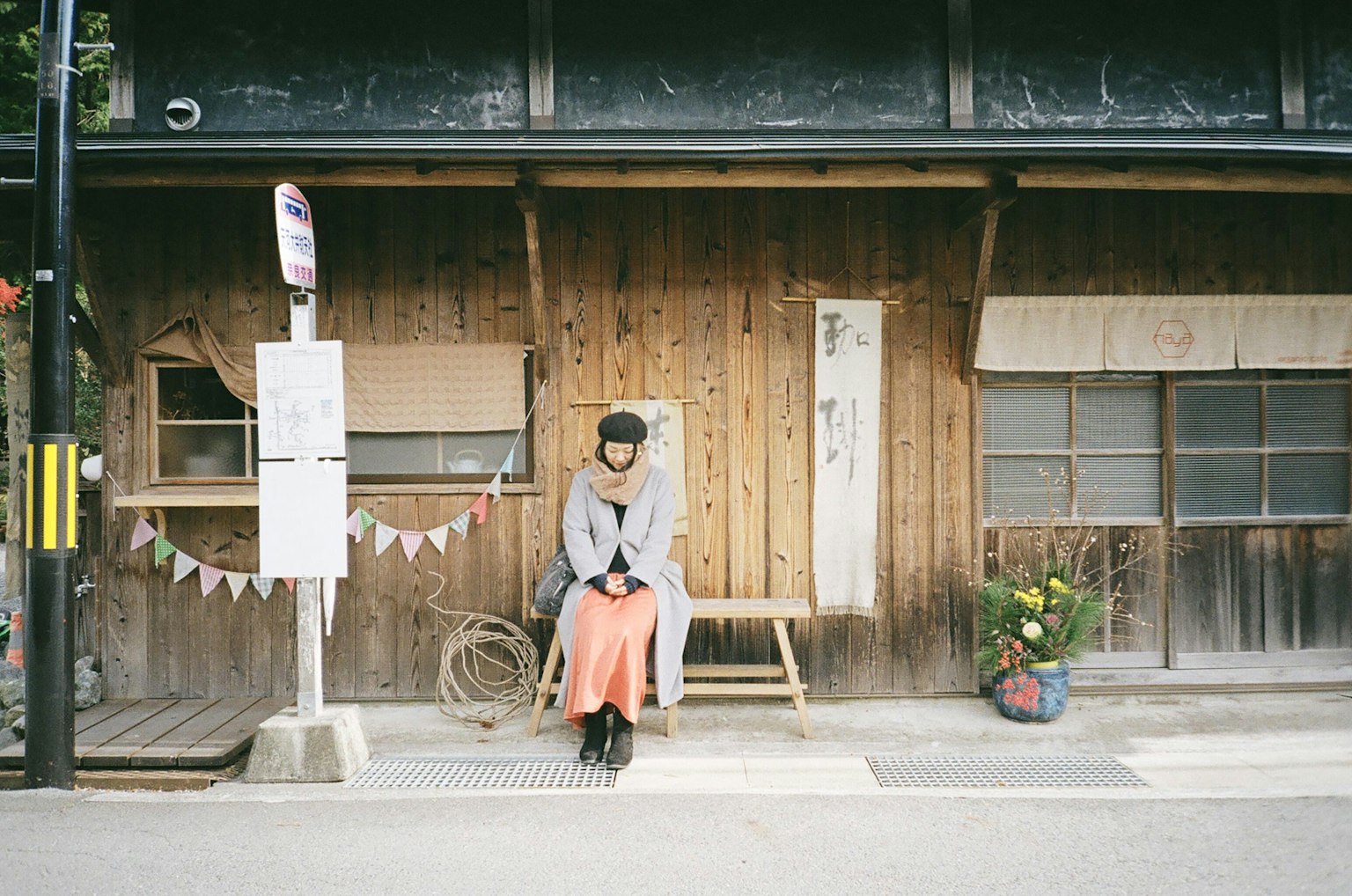 木造の家の前に座る女性　カジュアルな服装　穏やかな雰囲気