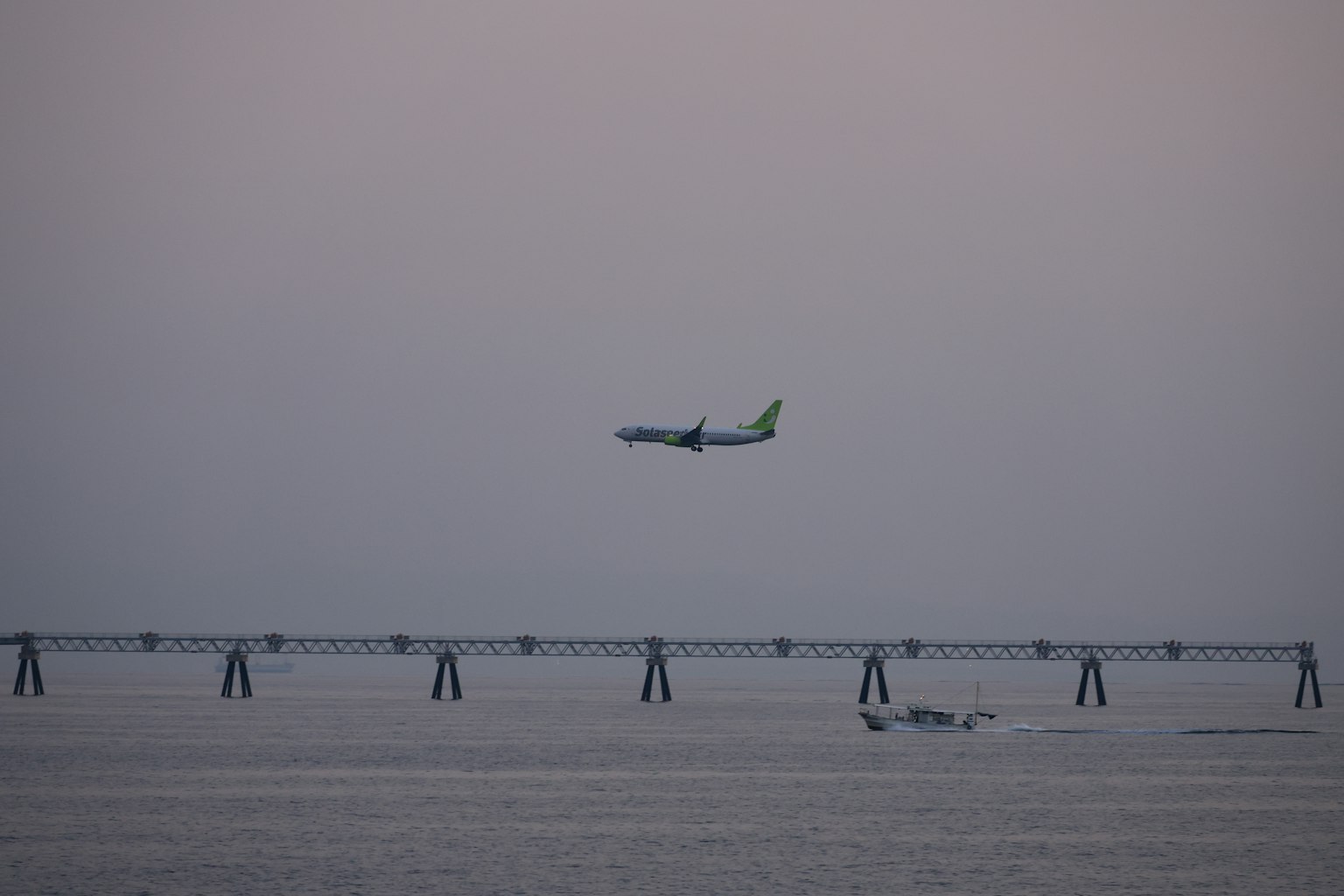 Aereo che vola sopra il mare con riflessi sull'acqua