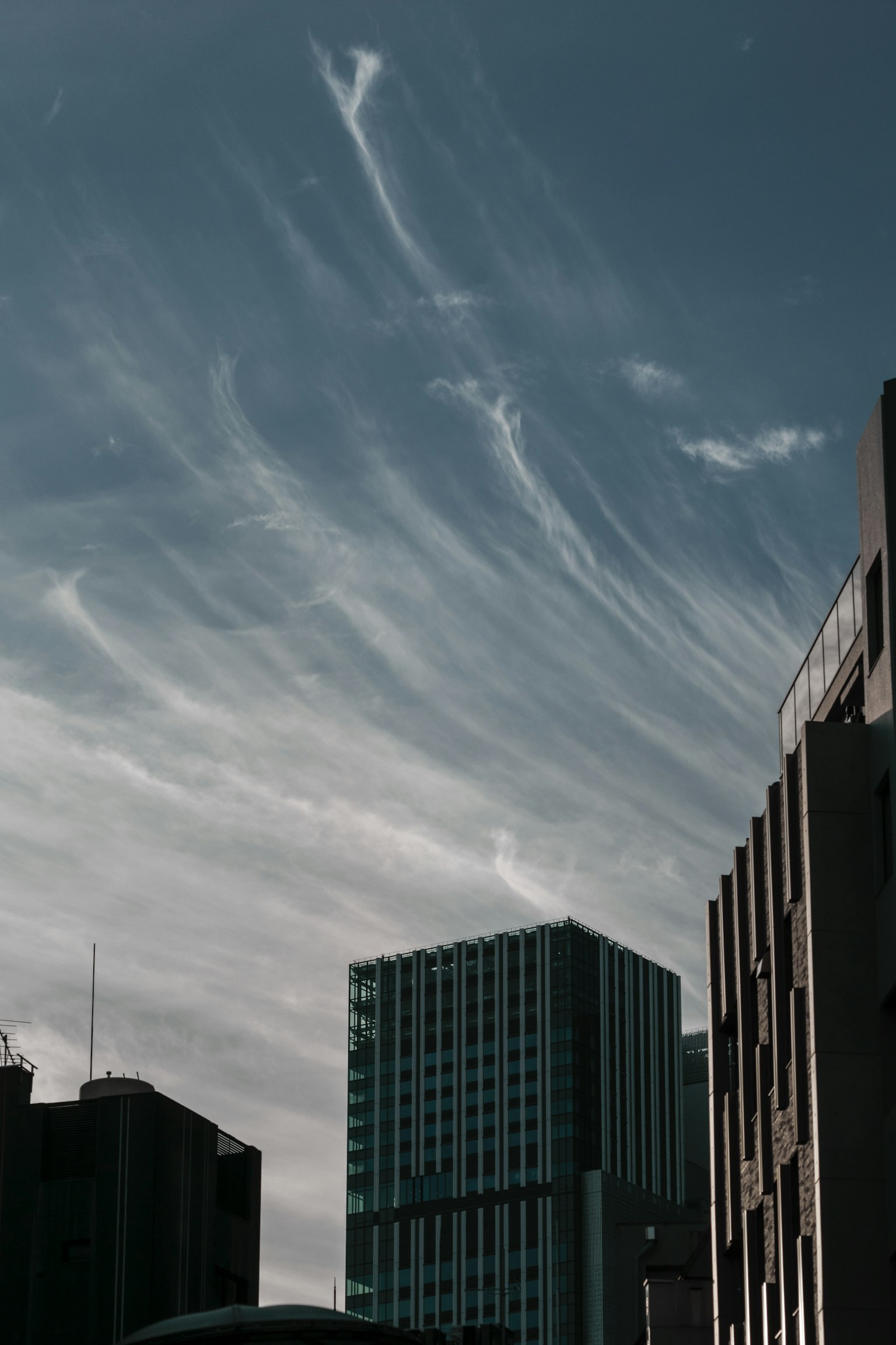 Silhouette bangunan di latar belakang langit biru dengan awan tipis