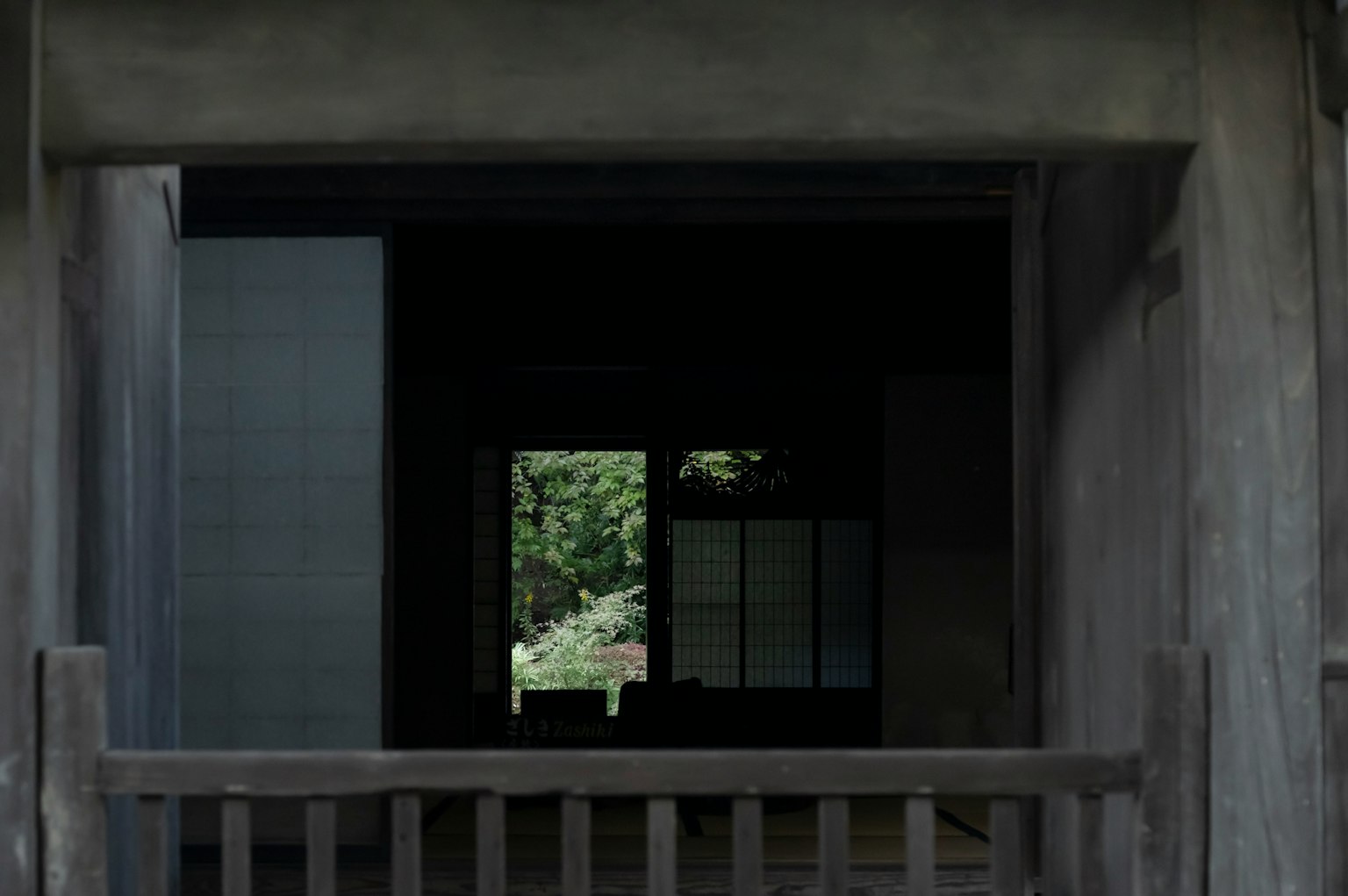 Vue d'un jardin à travers une entrée sombre d'une maison japonaise traditionnelle