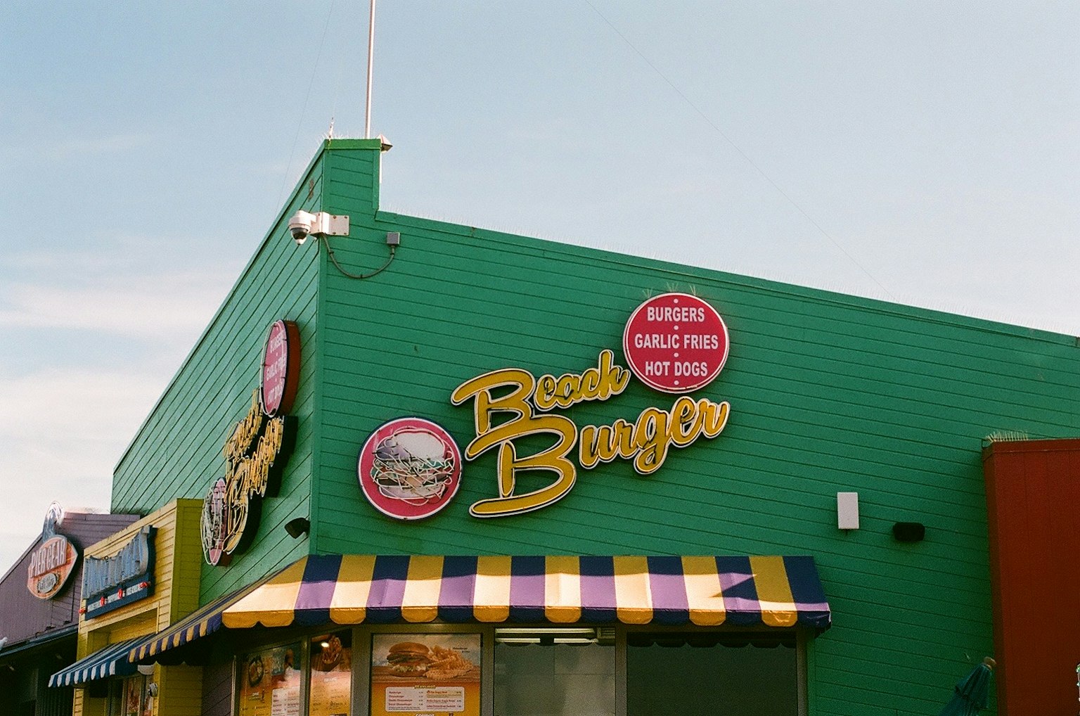Fachada colorida de Beach Burger con paredes verdes y toldo a rayas