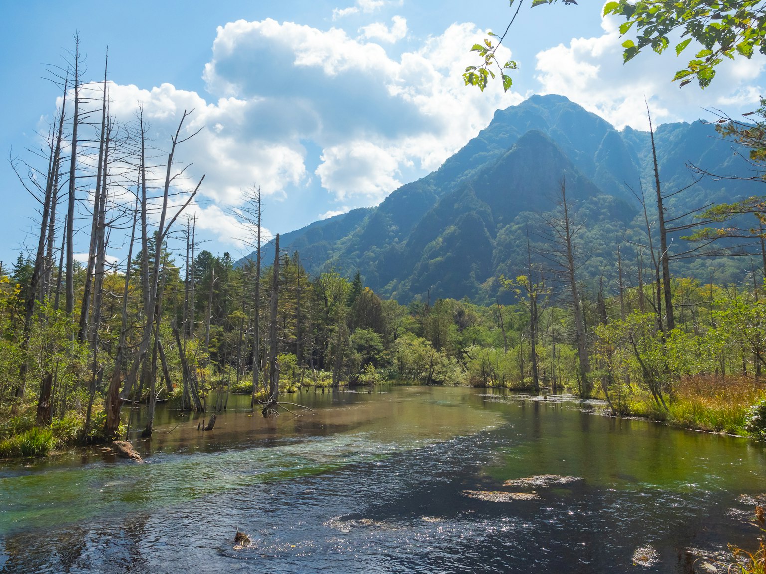 A serene river landscape with mountains and blue skies