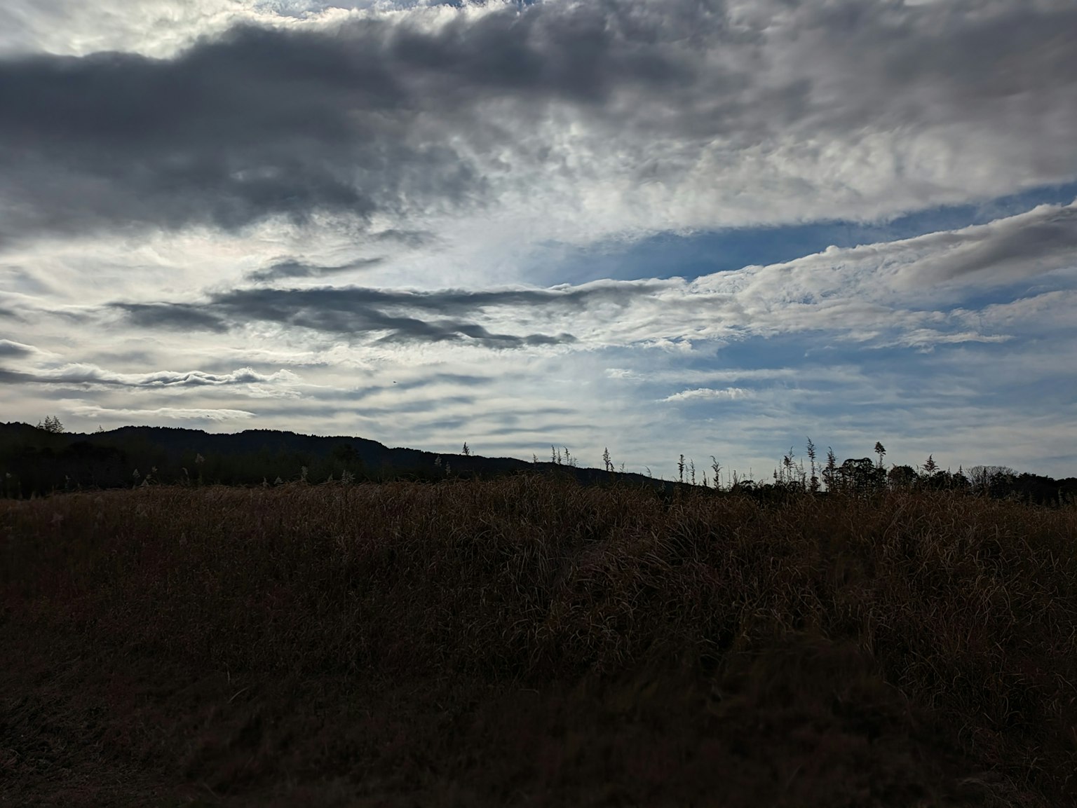 Landschaft mit weitem Himmel und silhouettierten Wolken