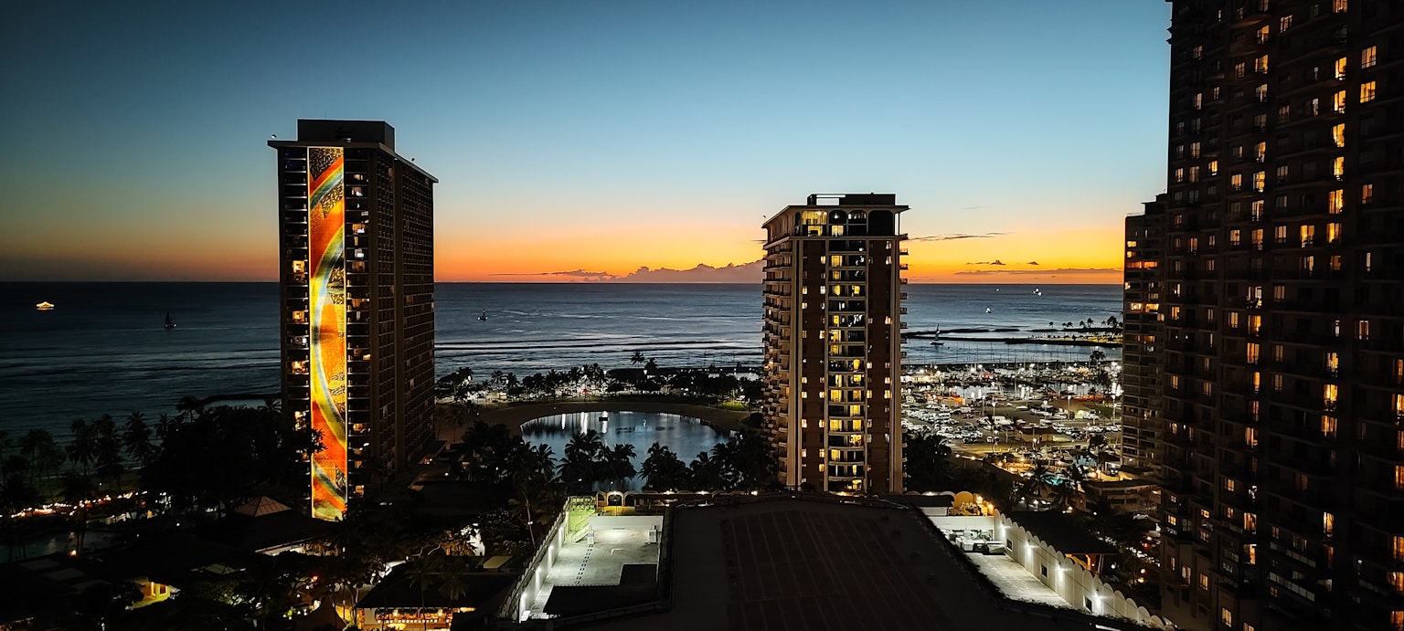Sunset view over the ocean with illuminated skyscrapers