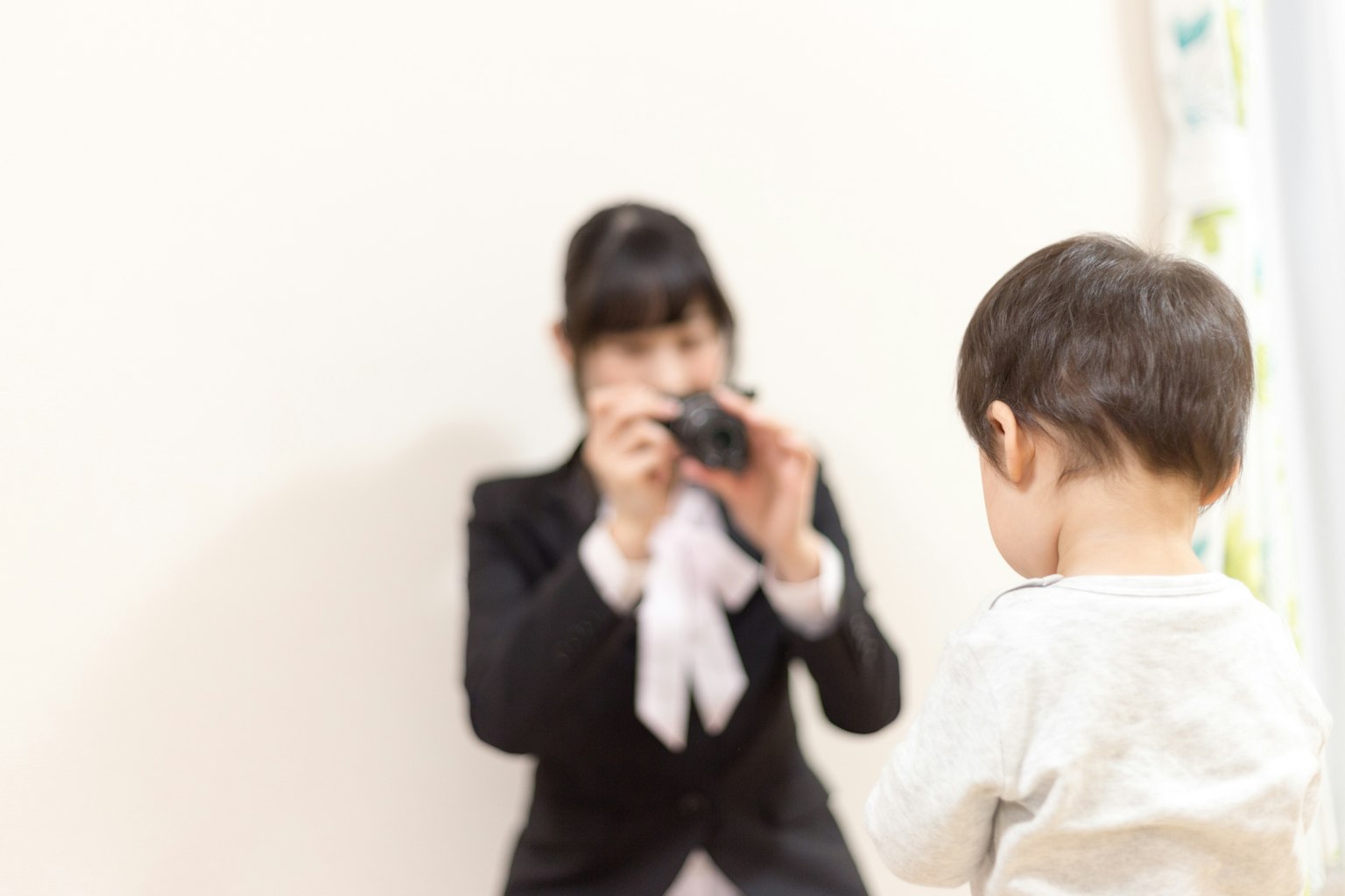 A woman with a camera capturing a child's back view
