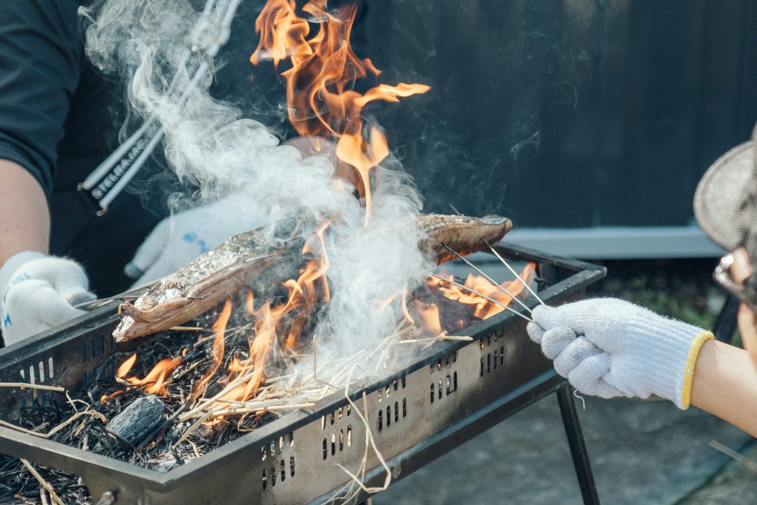 Grillage de poisson sur une flamme ouverte avec de la fumée et du feu