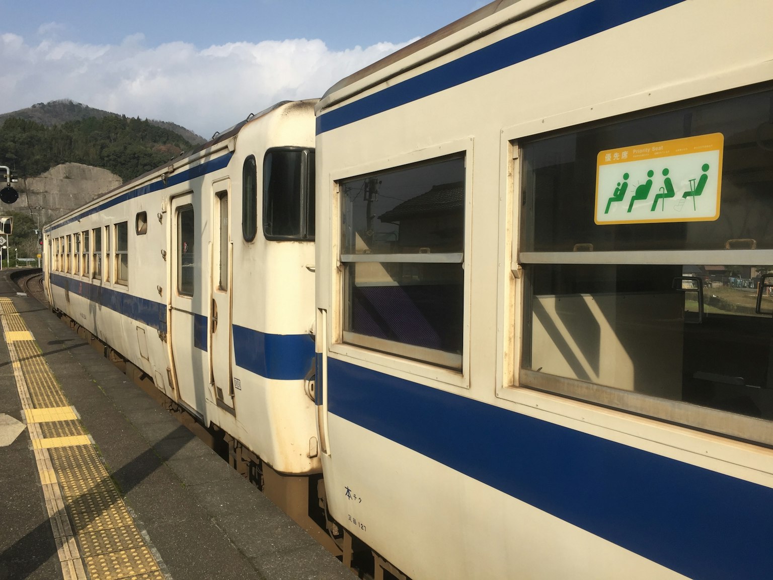 Un treno con strisce blu è fermo a una banchina della stazione