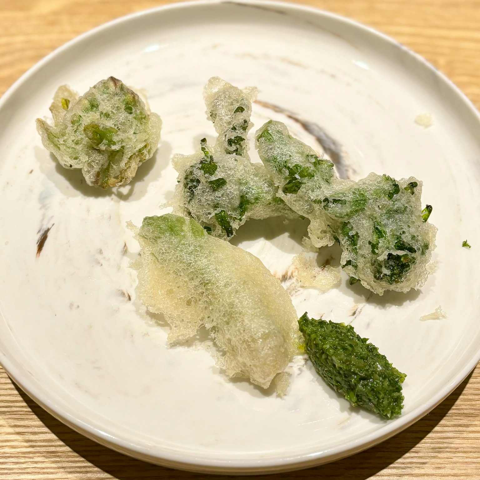 Fragments de tempura sur une assiette blanche avec des légumes verts