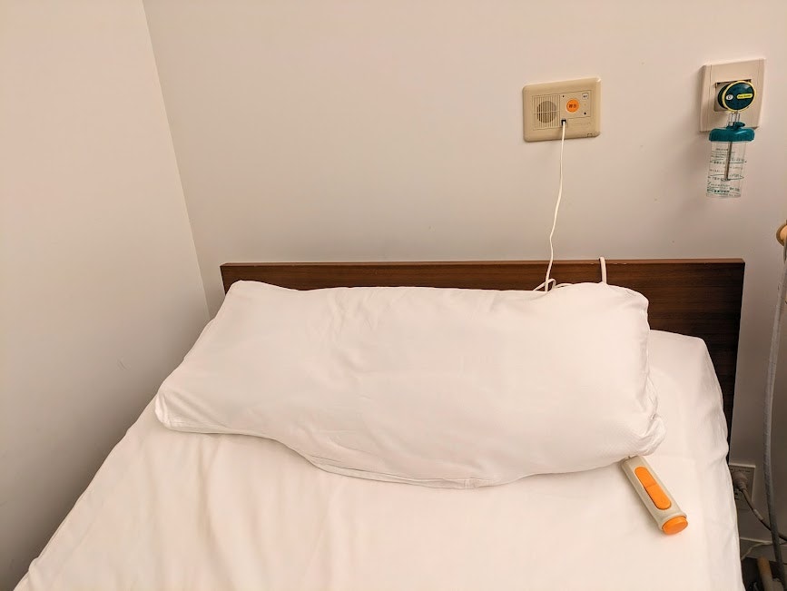 coin de chambre avec lit, oreillers et prises murales