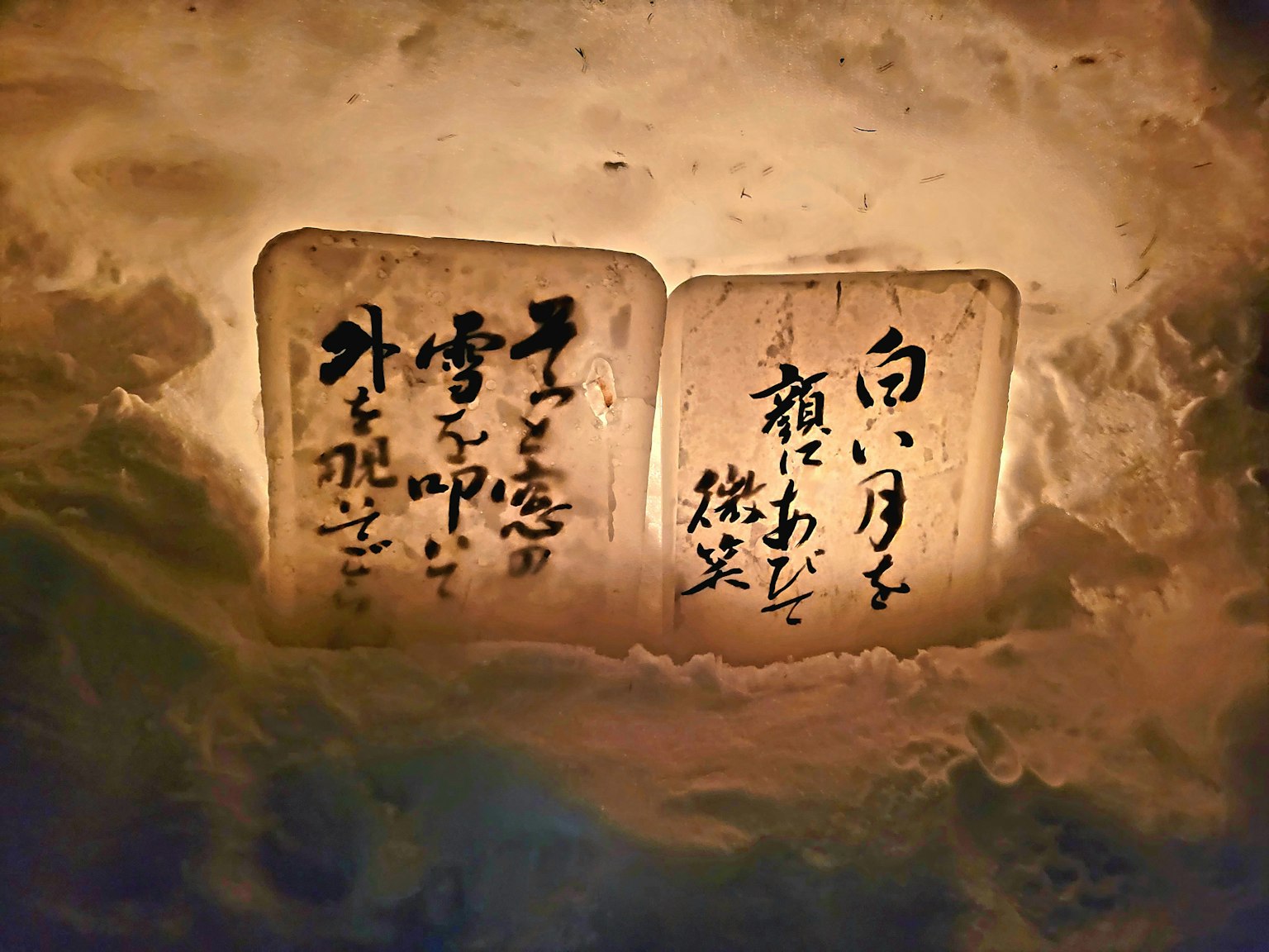 雪中两块带有日本书法的木牌被照亮