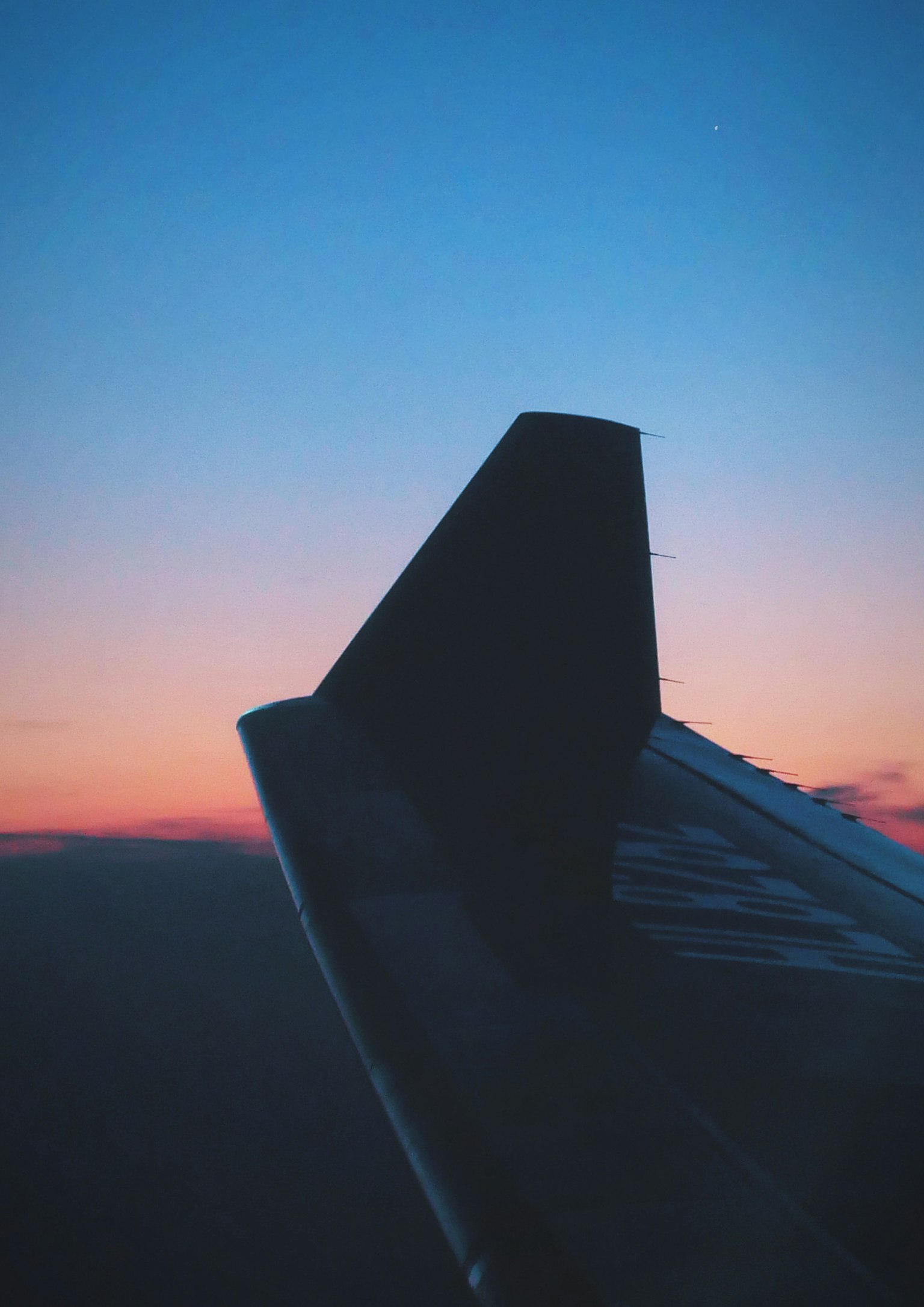 Silhouette d'une aile d'avion contre un ciel au coucher du soleil