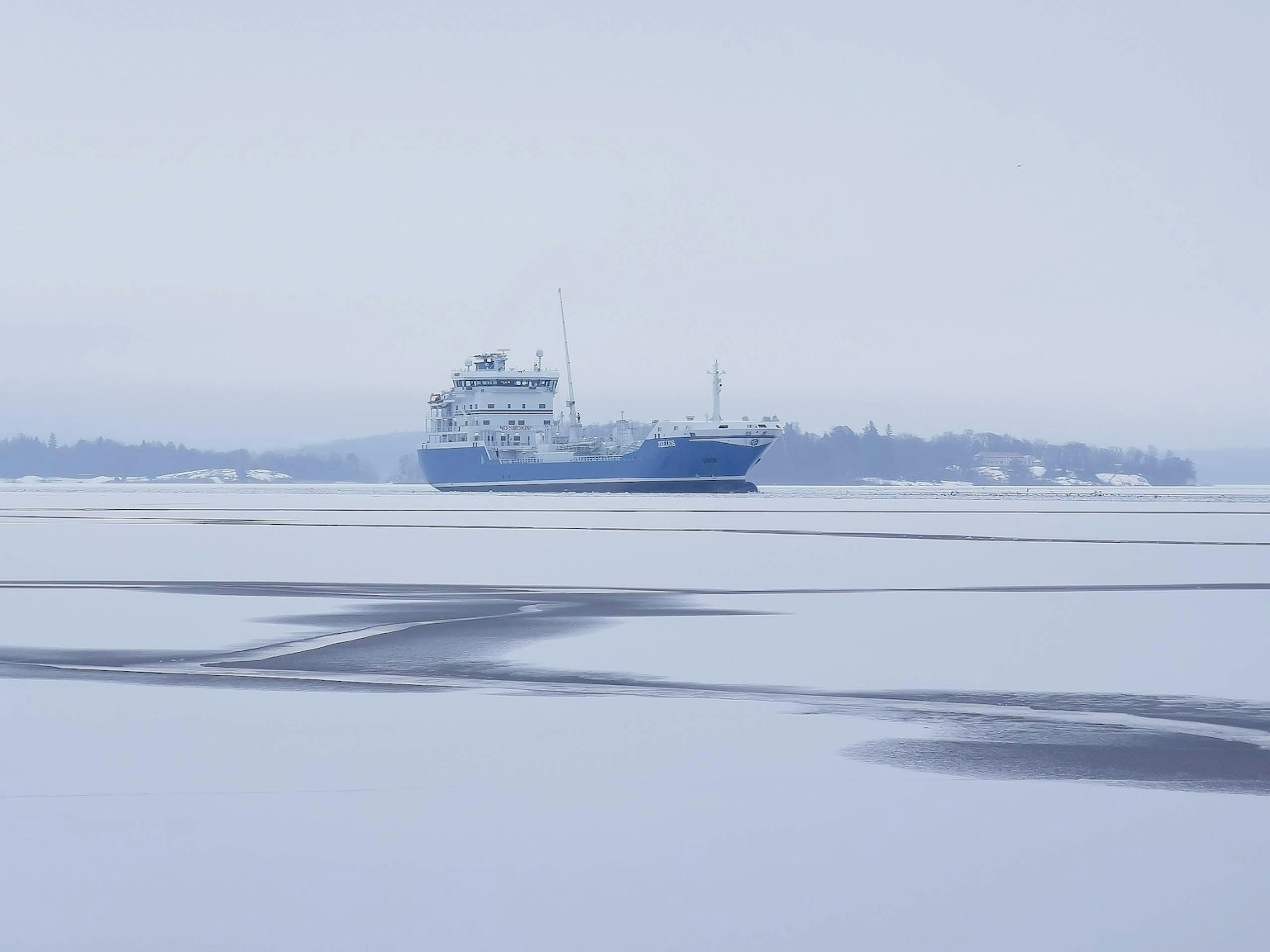 Bateau de fret bleu flottant sur la mer gelée
