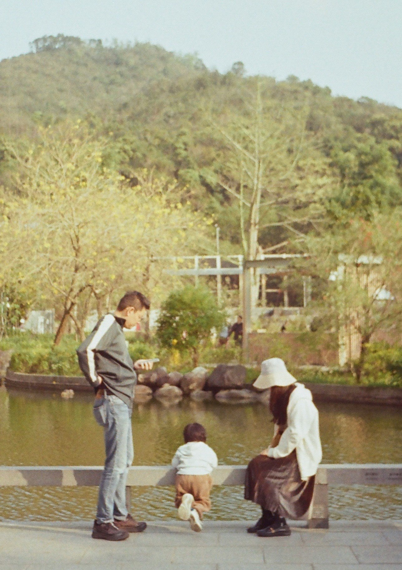 池のほとりで釣りをする人々と緑の丘の風景
