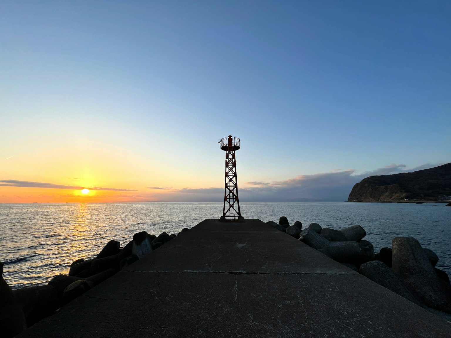 Belle vue d'un quai avec la silhouette d'un phare au coucher du soleil sur l'océan