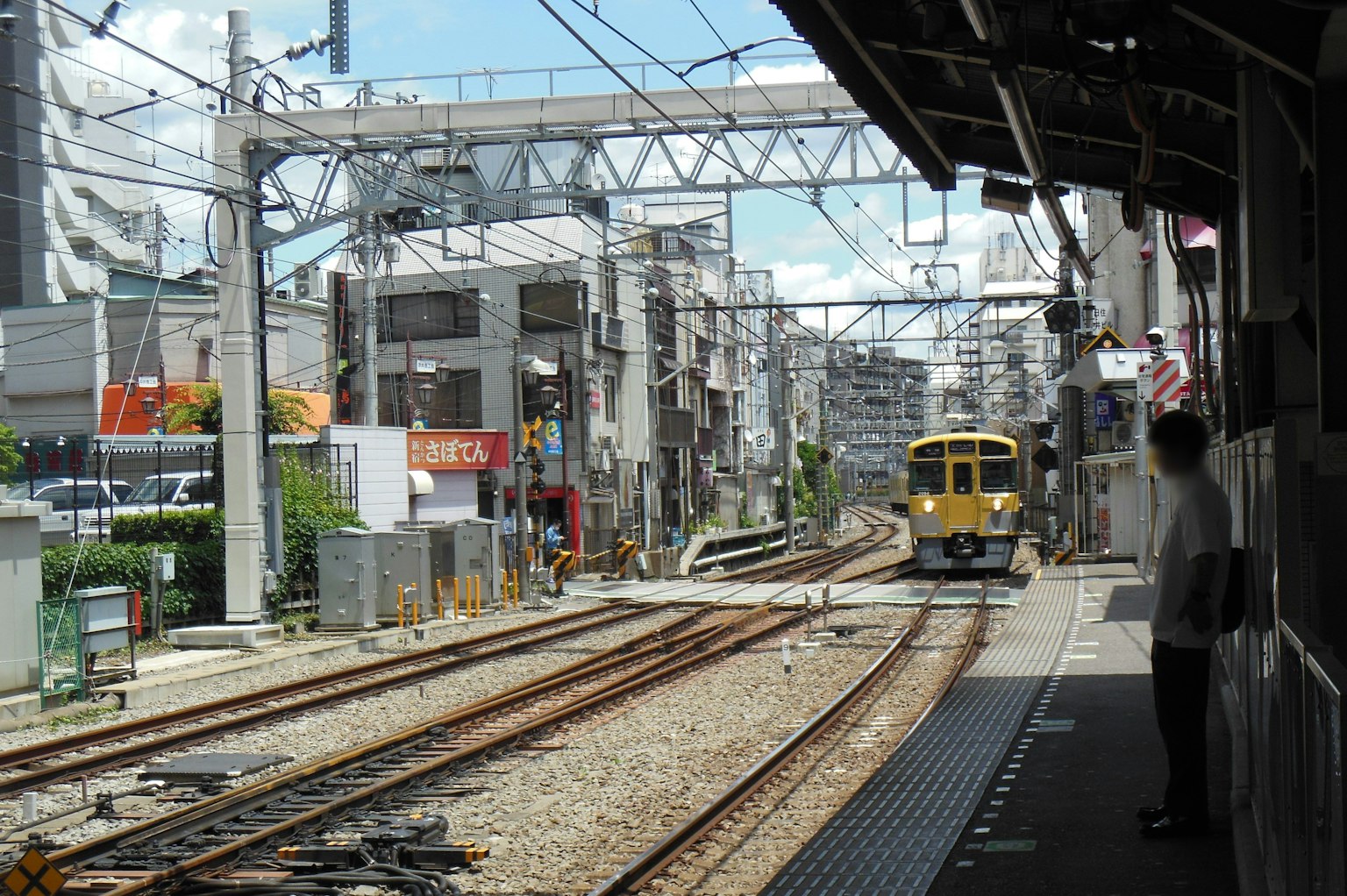 一列火車駛向車站，背景是商業建築和藍天