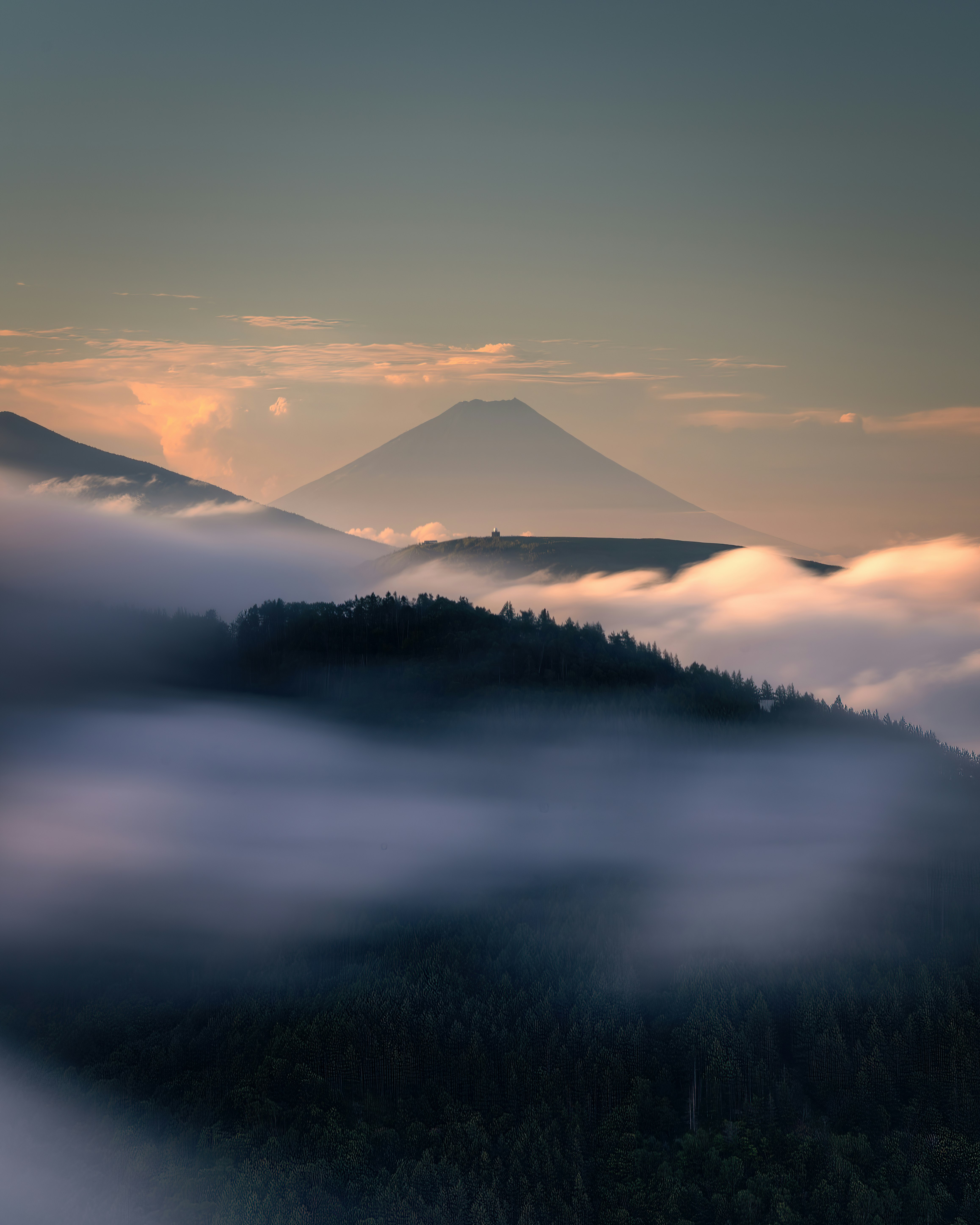 霧に包まれた山並みと森の朝景
