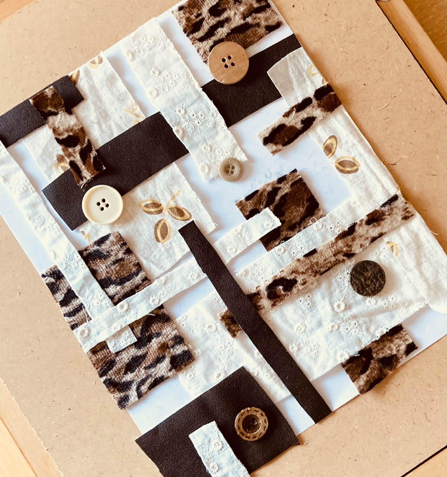 用白色和棕色布料製作的拼貼藝術，具有鈕扣和獨特的圖案