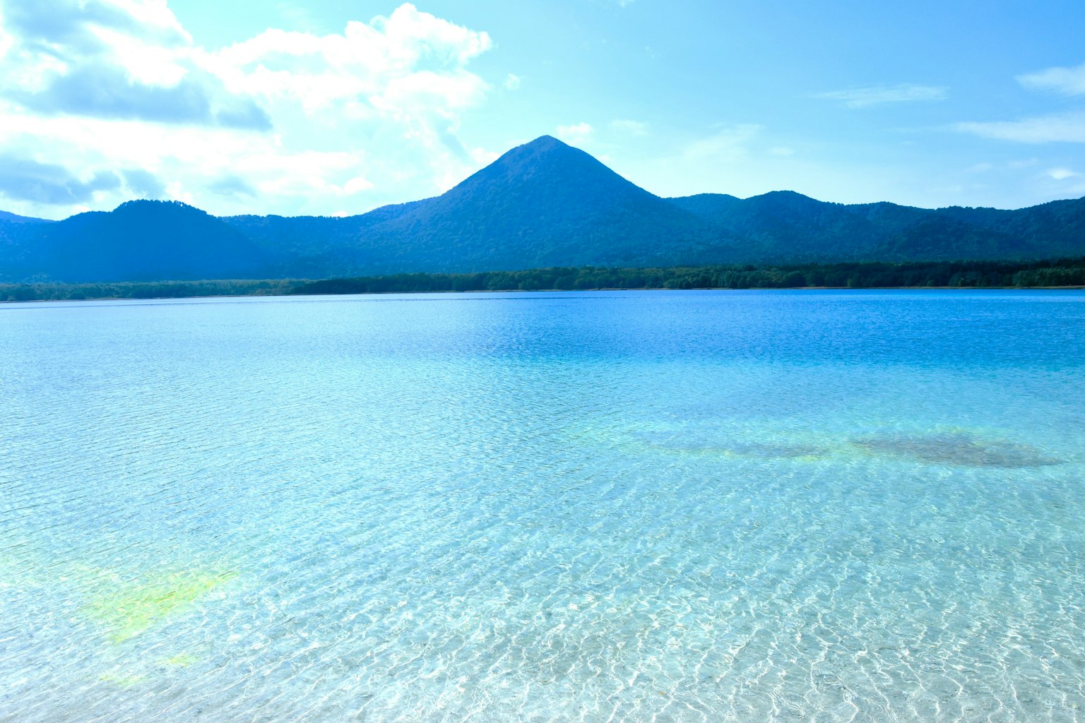 ทิวทัศน์ของทะเลสีฟ้าสดใสพร้อมภูเขาในพื้นหลัง