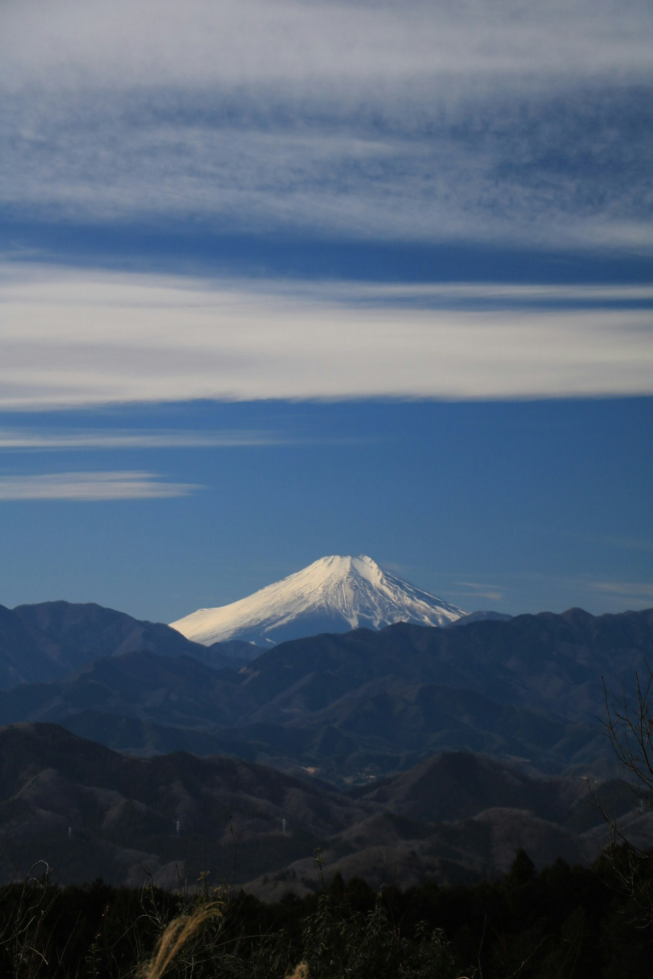 山並みの向こうにそびえる雪をかぶった火山のシルエット
